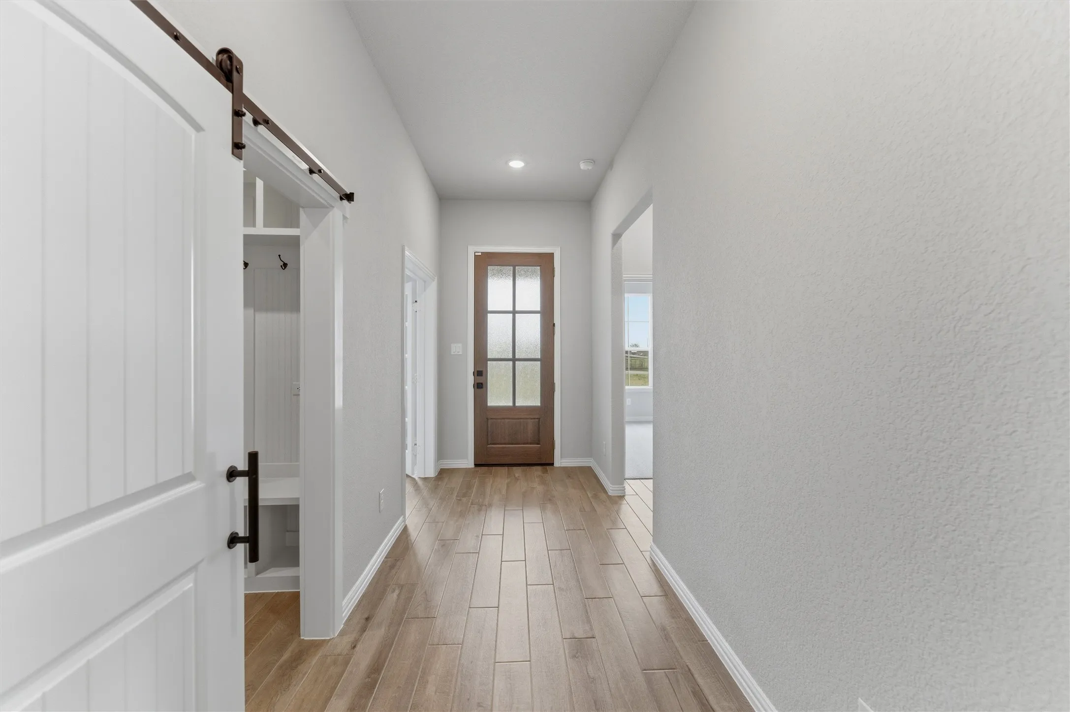Doorway with a barn door, wood finish floors, and recessed lighting