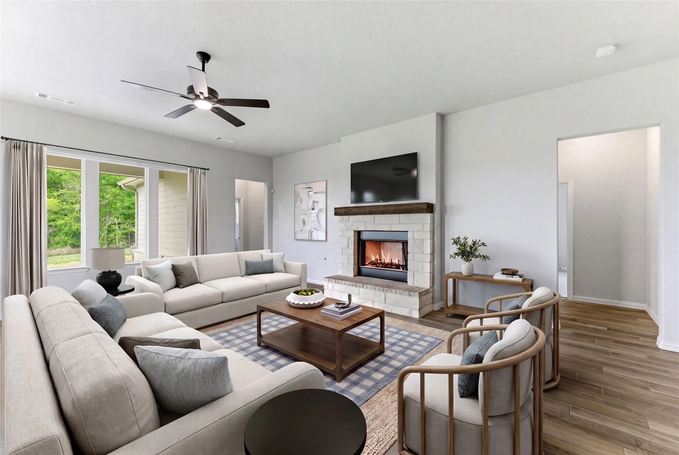 Living area featuring a stone-clad fireplace with a wood mantel, wood-finish flooring, and multiple windows