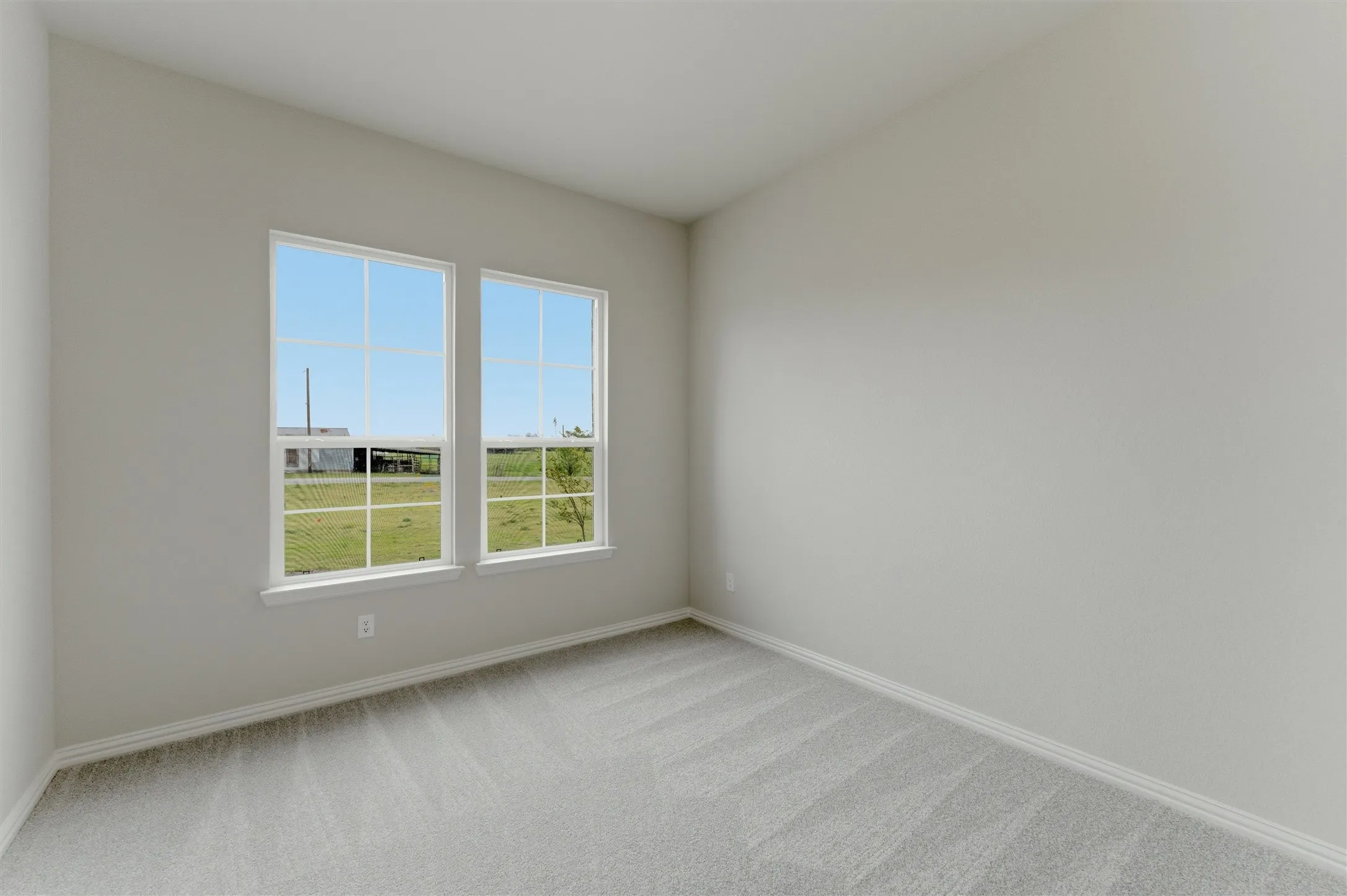 Unfurnished room featuring light carpet and baseboards