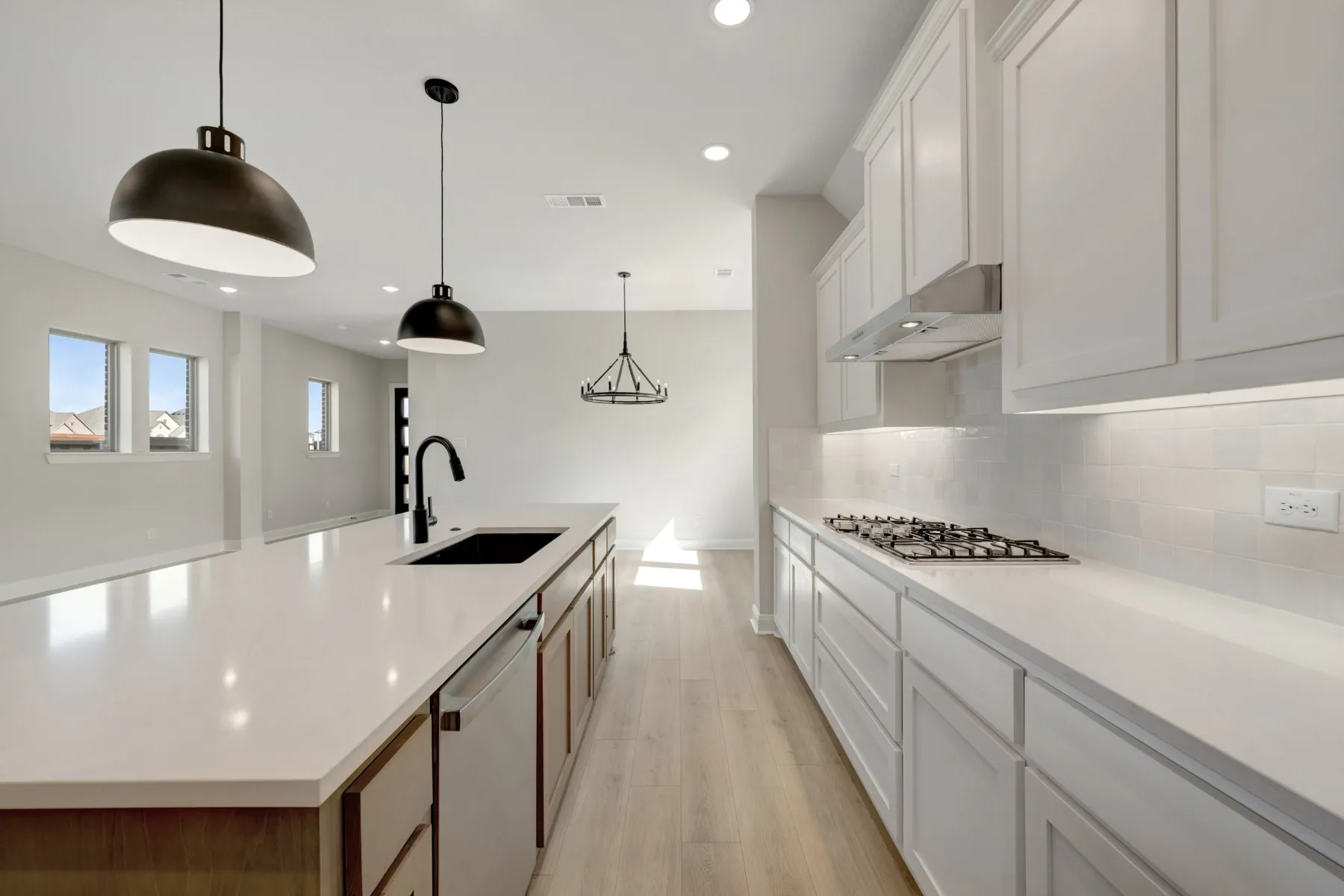 Two tone kitchen with a spacious island, pendant lighting, stainless steel appliances, light wood-style floors, and dual tone cabinetry