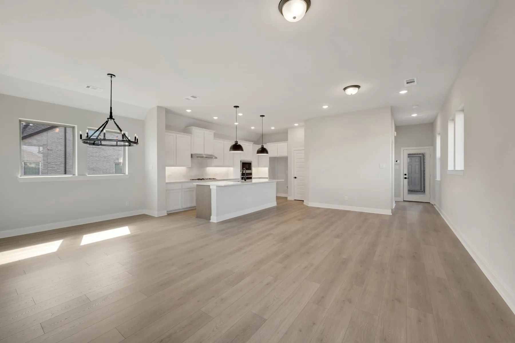 Unfurnished living room featuring light wood-style flooring and suspended lighting