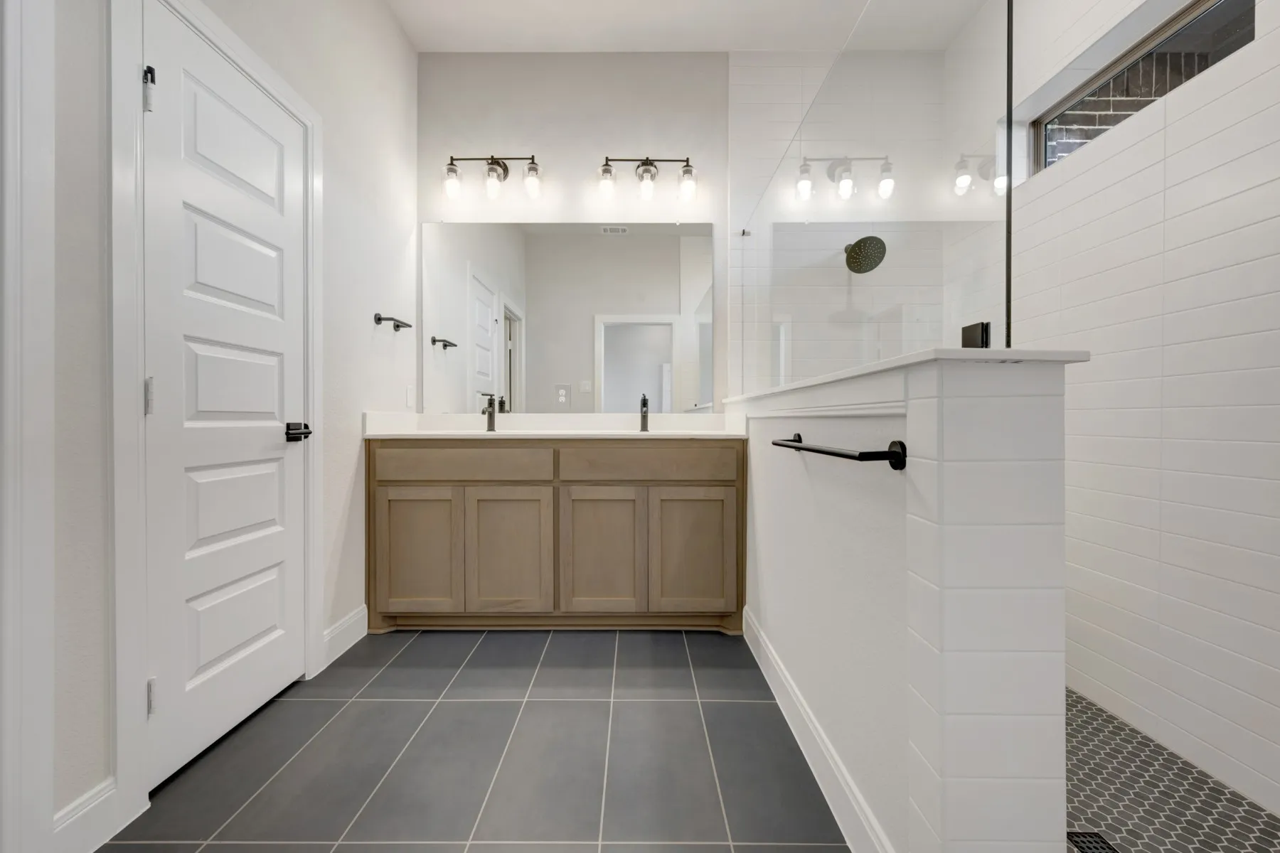 Full bath featuring double vanity, a walk in shower, and dark tile patterned flooring