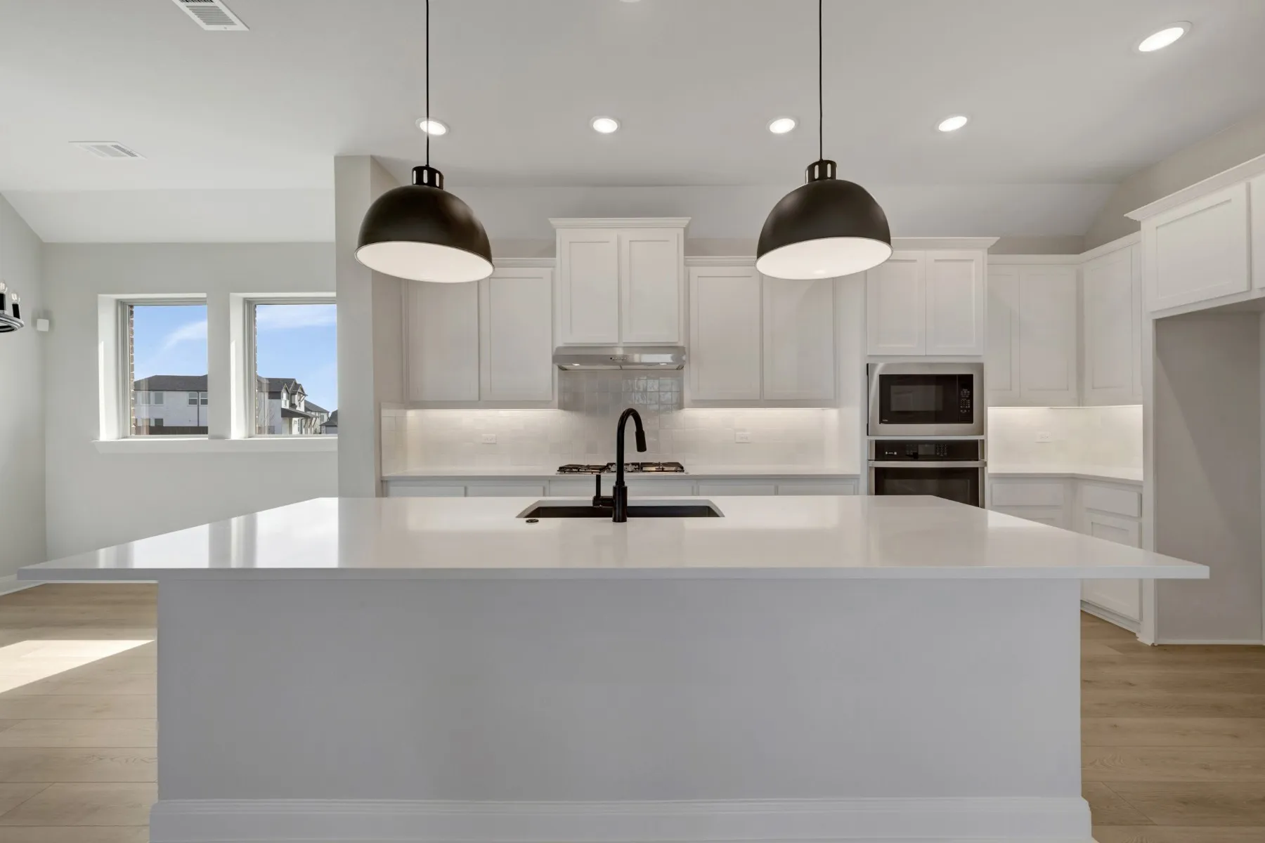 Kitchen with light wood-type flooring, white cabinets, a kitchen island with sink, and stainless steel appliances
