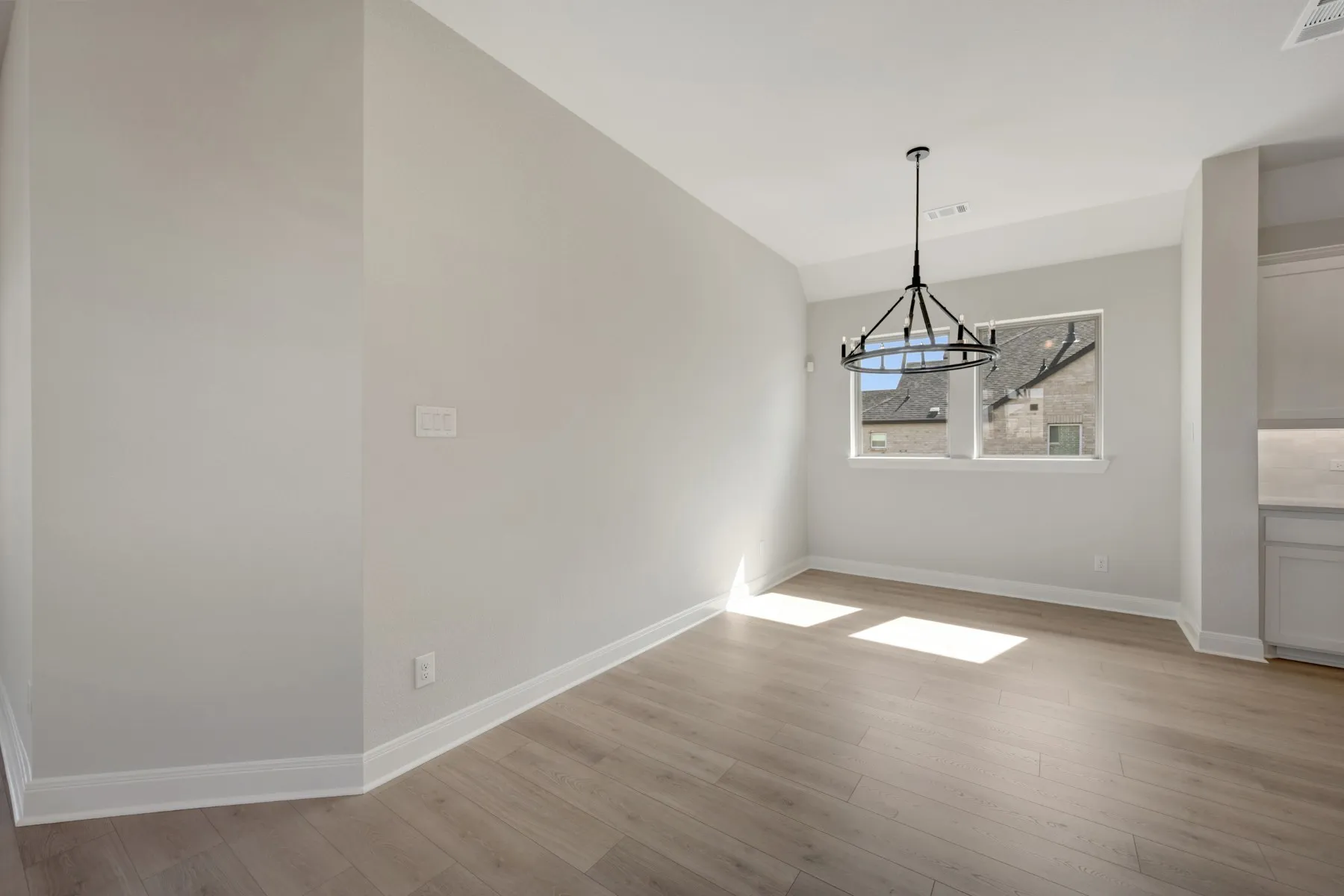 Unfurnished dining area with vaulted ceiling, light wood-type flooring, and suspended lighting