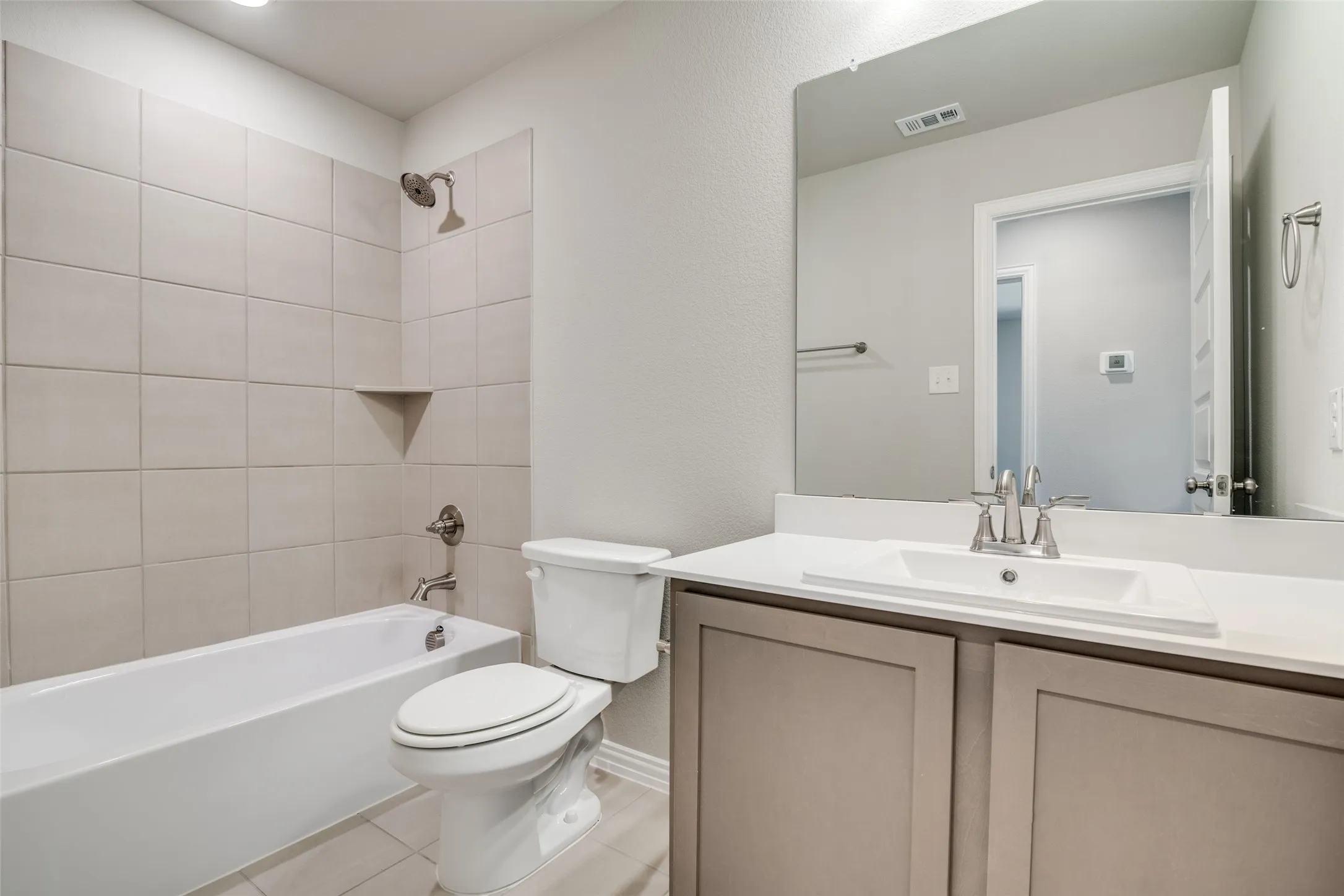 Bathroom with washtub / shower combination, vanity, and light tile patterned flooring
