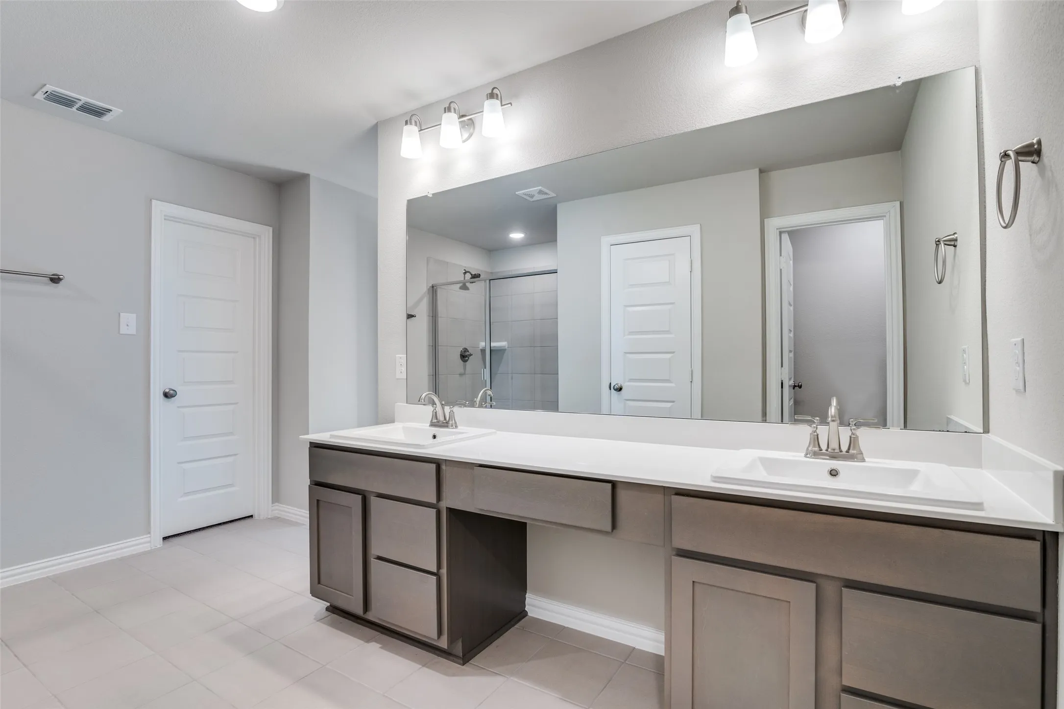 Full bathroom with a shower stall, double vanity, recessed lighting, and light tile patterned floors