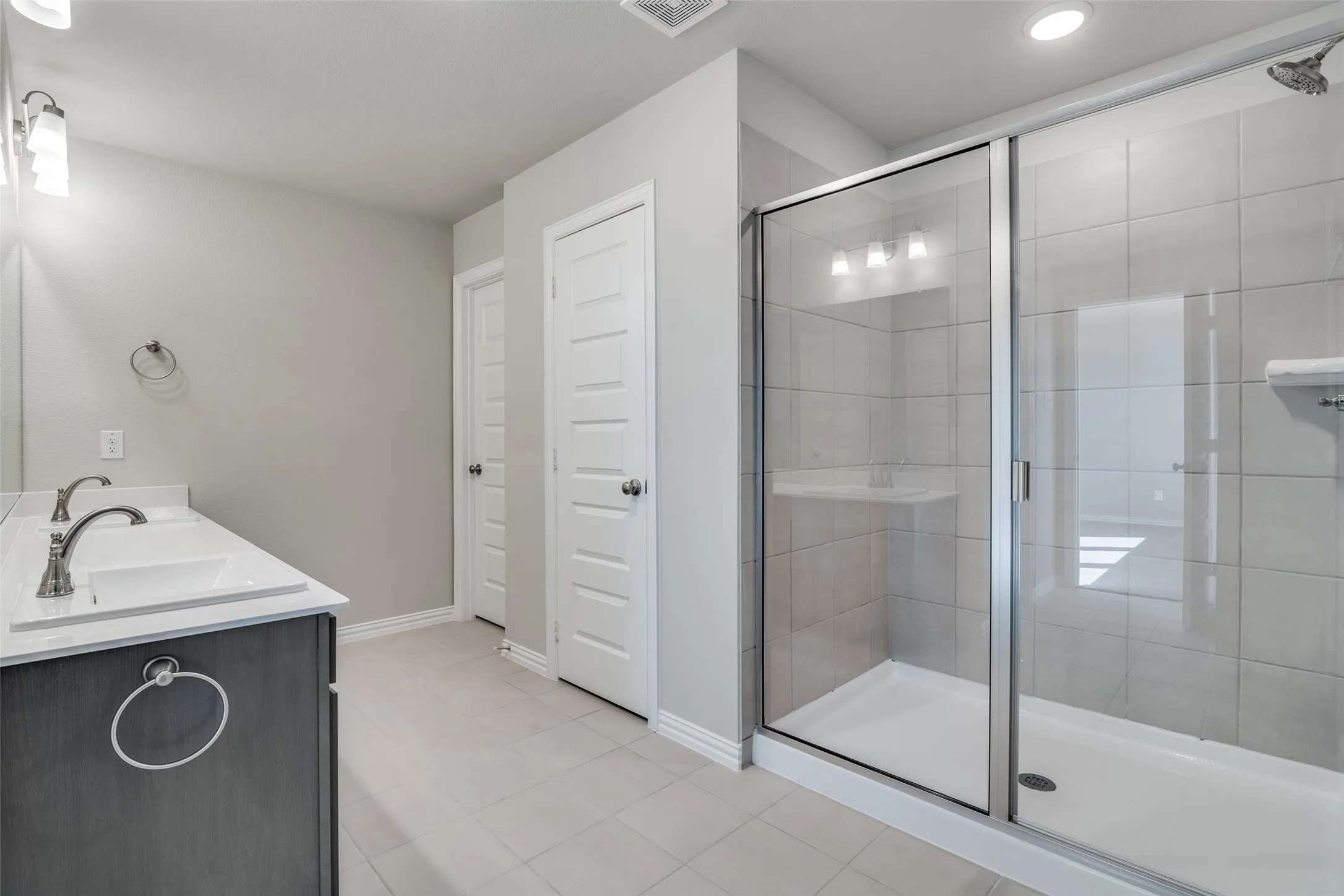Full bathroom with a stall shower, double vanity, and light tile patterned floors