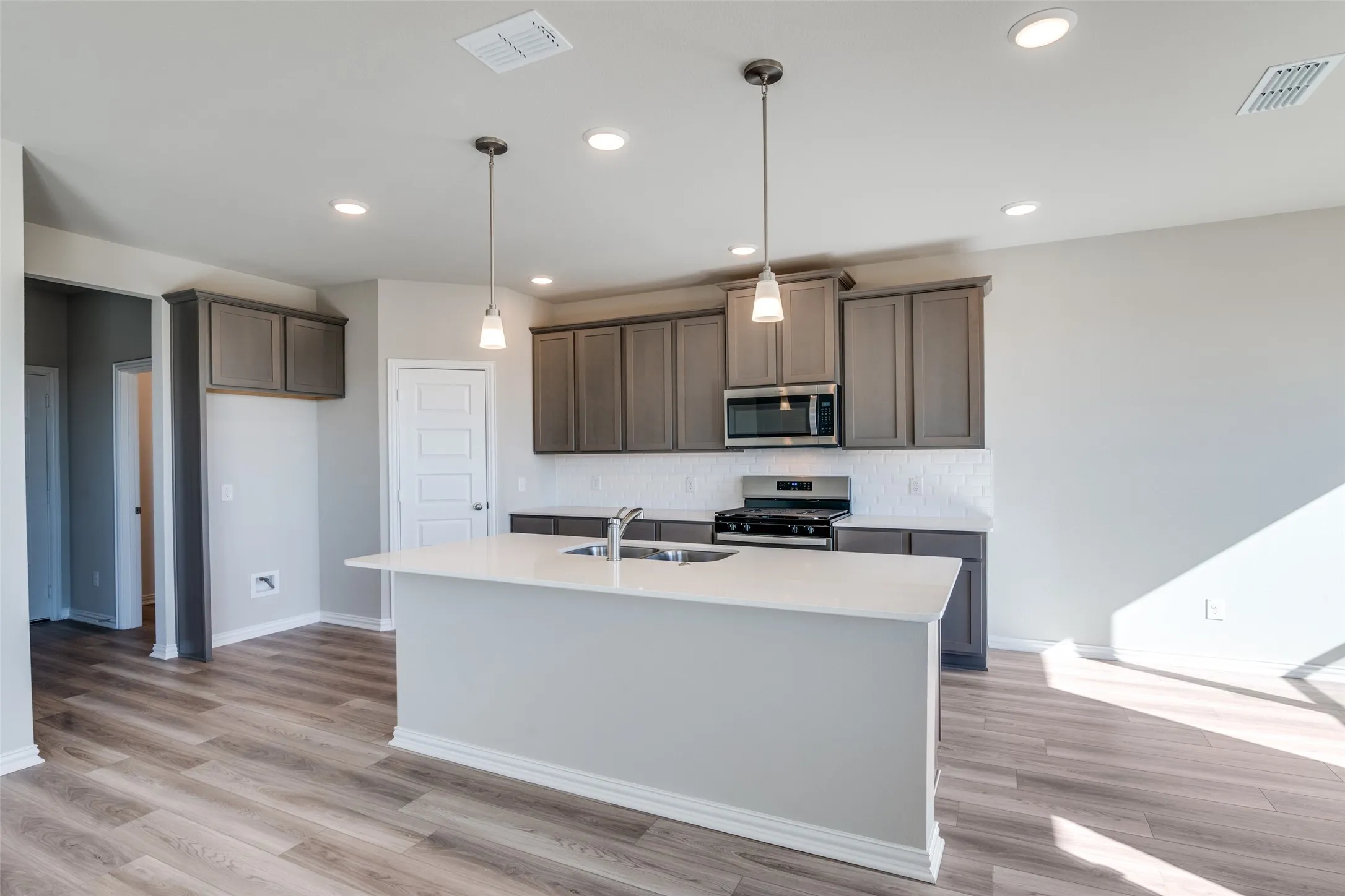 Kitchen with appliances with stainless steel finishes, decorative backsplash, decorative light fixtures, an island with sink, and recessed lighting