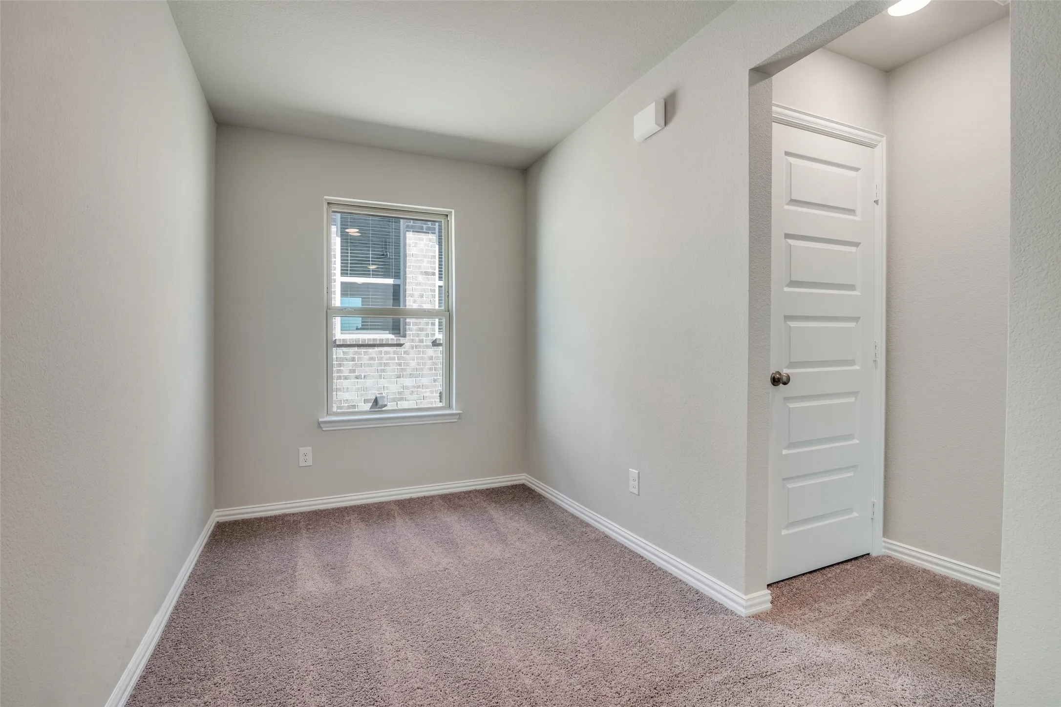 Empty room with light colored carpet and baseboards