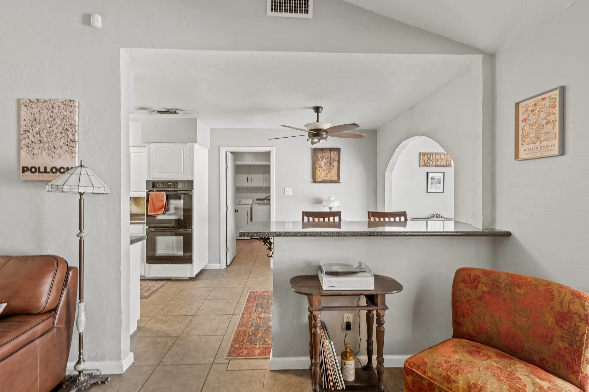 Kitchen with a breakfast bar, light tile patterned floors, white cabinets, independent washer and dryer, and a ceiling fan