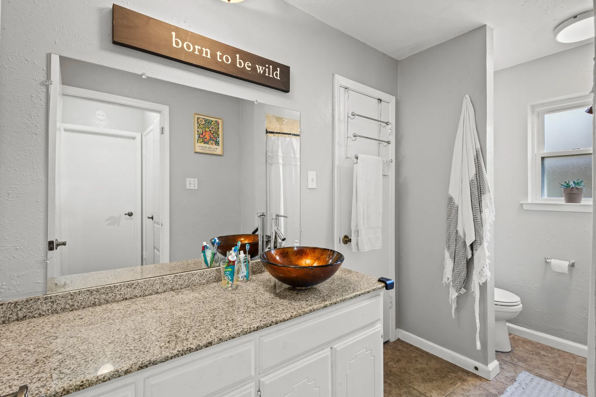 Full bathroom featuring vanity, dark tile patterned floors, a textured wall, and a shower with shower curtain