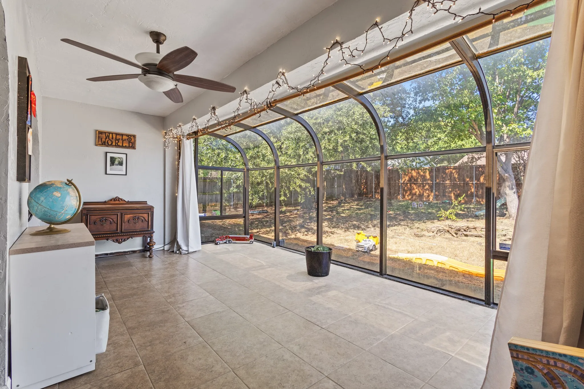 Sunroom featuring ceiling fan and view of scattered trees