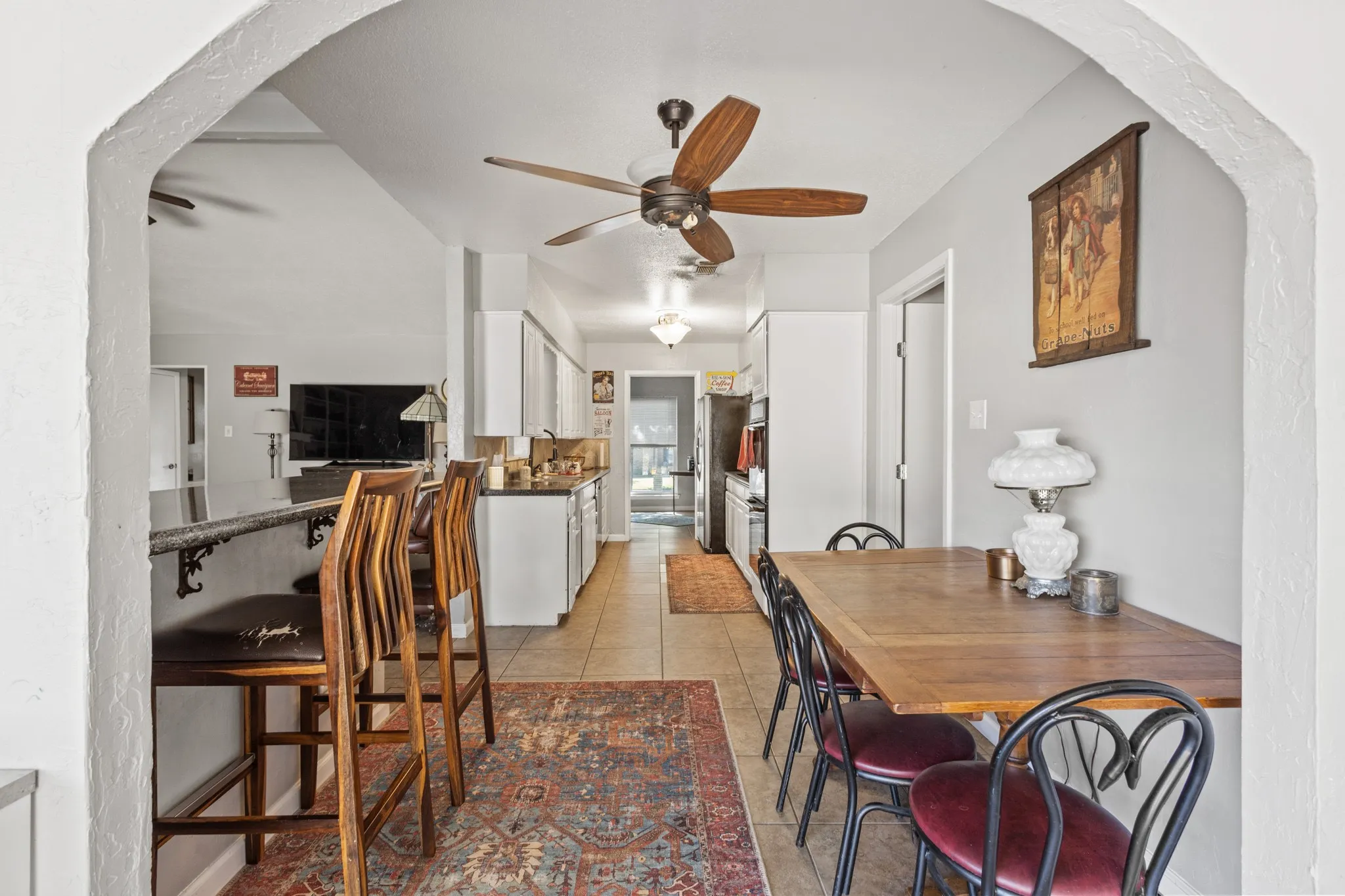 Dining room with light tile patterned floors, arched walkways, and ceiling fan