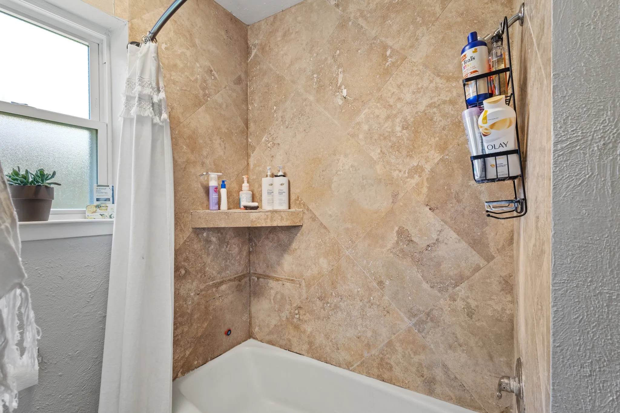 Bathroom featuring a textured wall and shower / bath combo with shower curtain