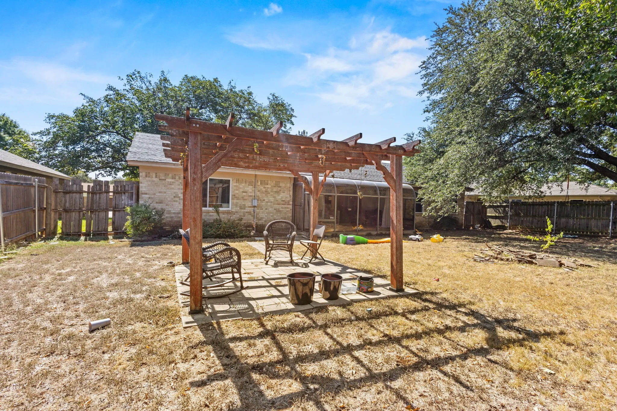 Back of house featuring a patio, a fenced backyard, a pergola, and brick siding