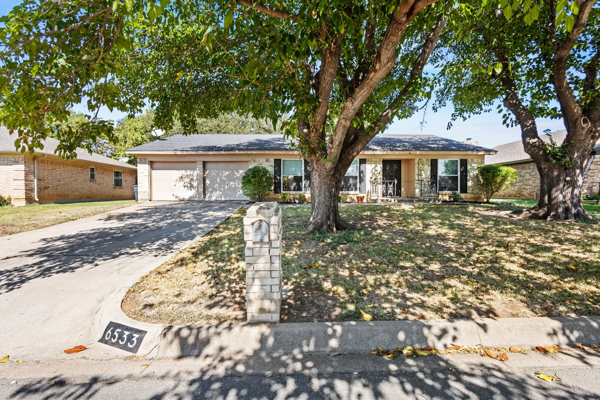 Ranch-style home with concrete driveway, an attached garage, a porch, and brick siding