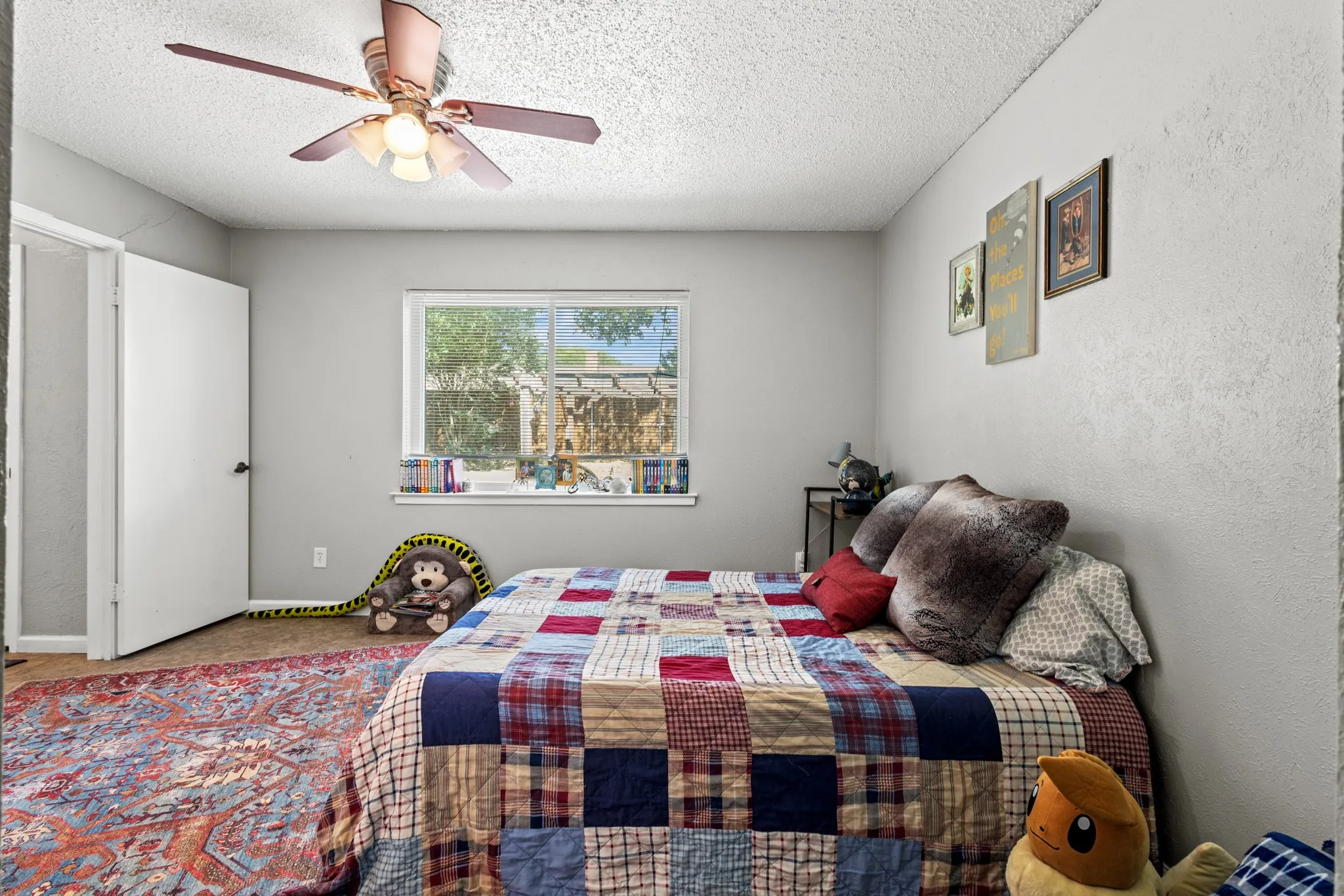 Carpeted bedroom with a textured ceiling, a ceiling fan, and a textured wall