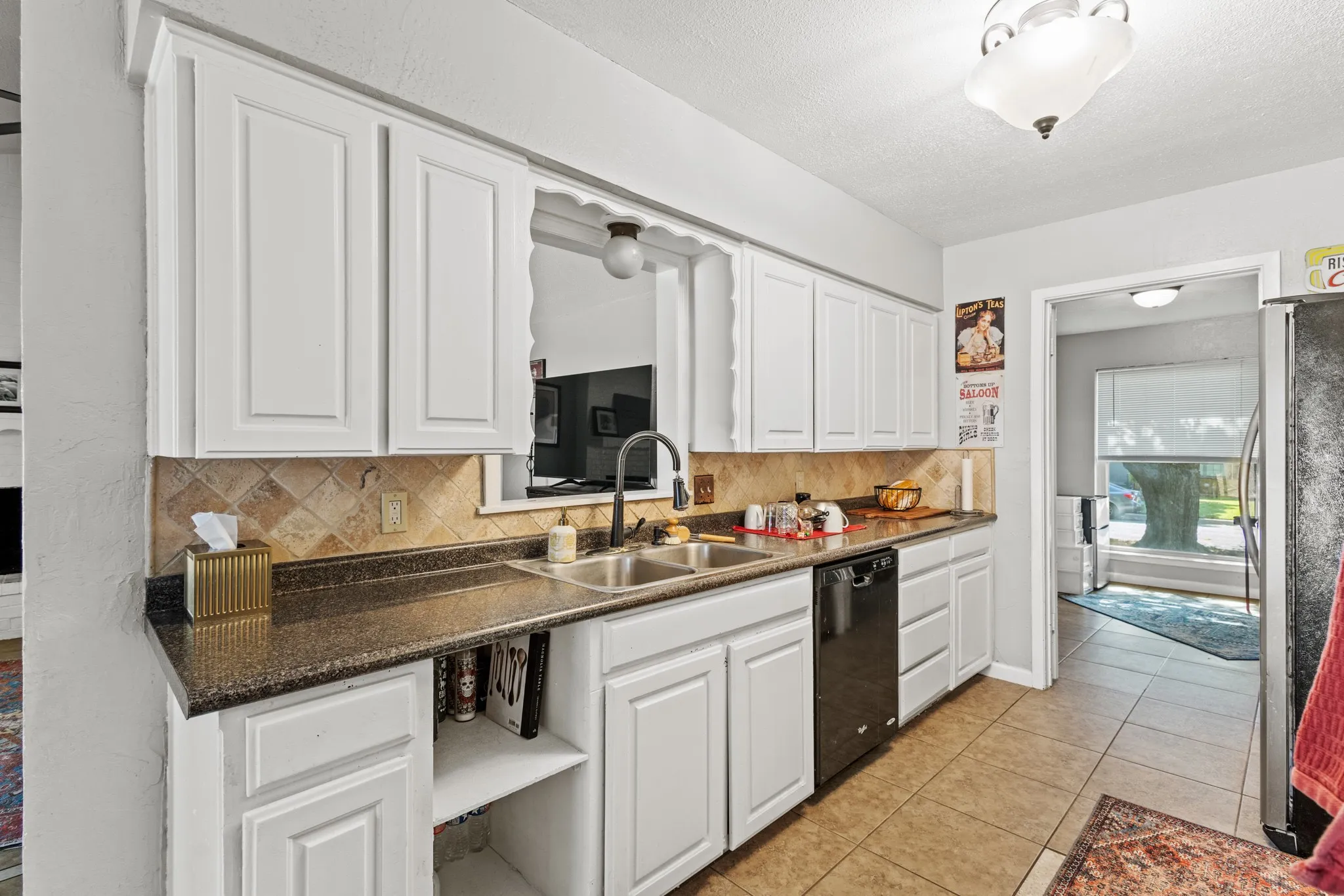 Kitchen featuring white cabinetry, decorative backsplash, freestanding refrigerator, light tile patterned floors, and dishwasher