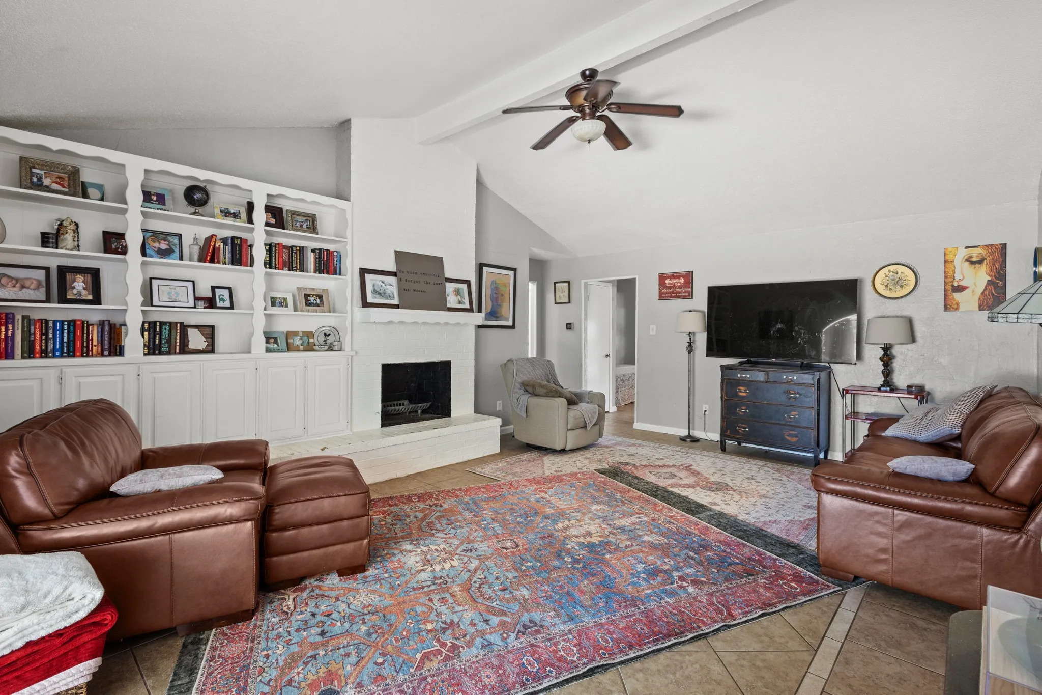 Tiled living area featuring a fireplace with raised hearth and ceiling fan