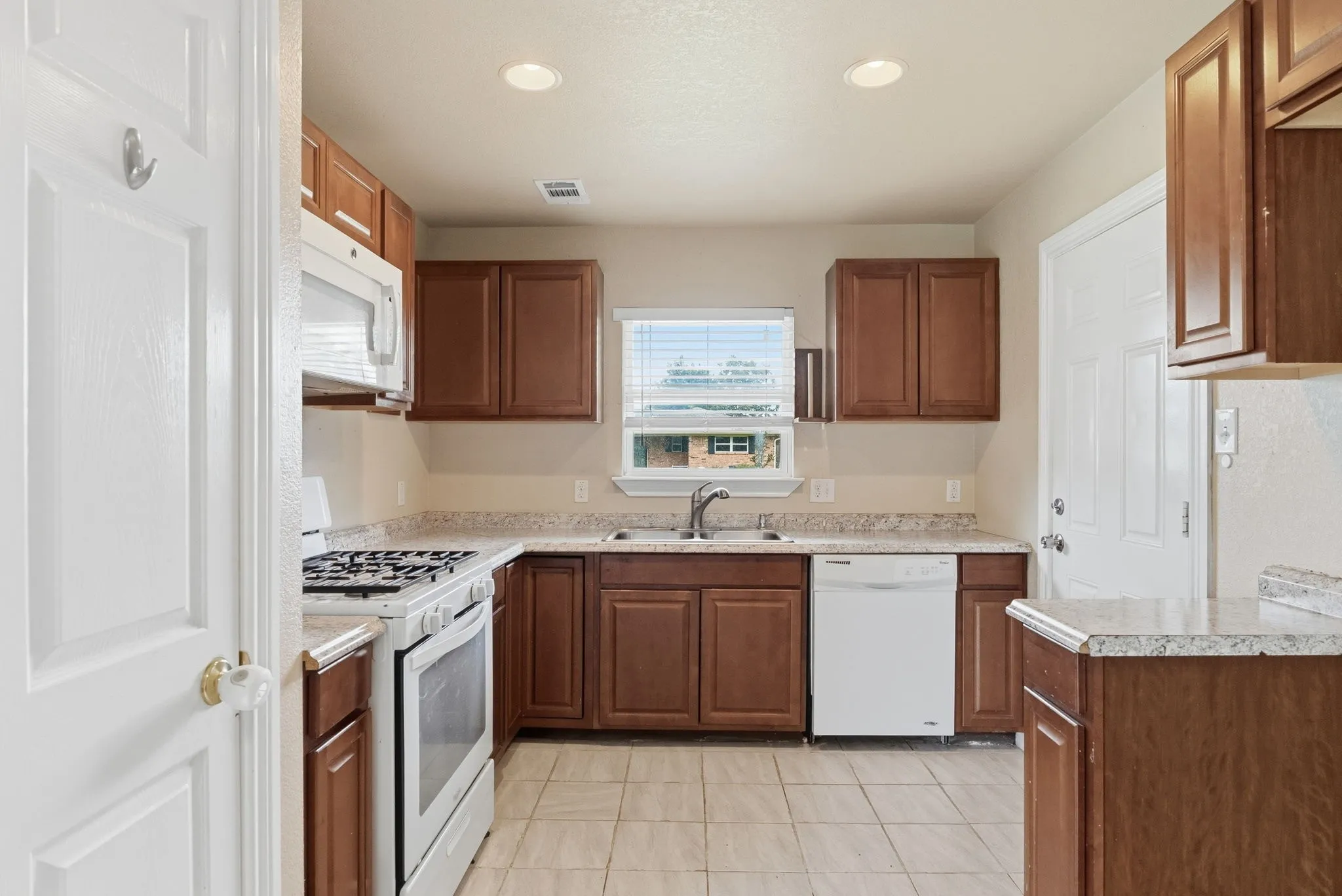 Kitchen featuring wood-finish cabinetry, light-toned countertops, and tile flooring