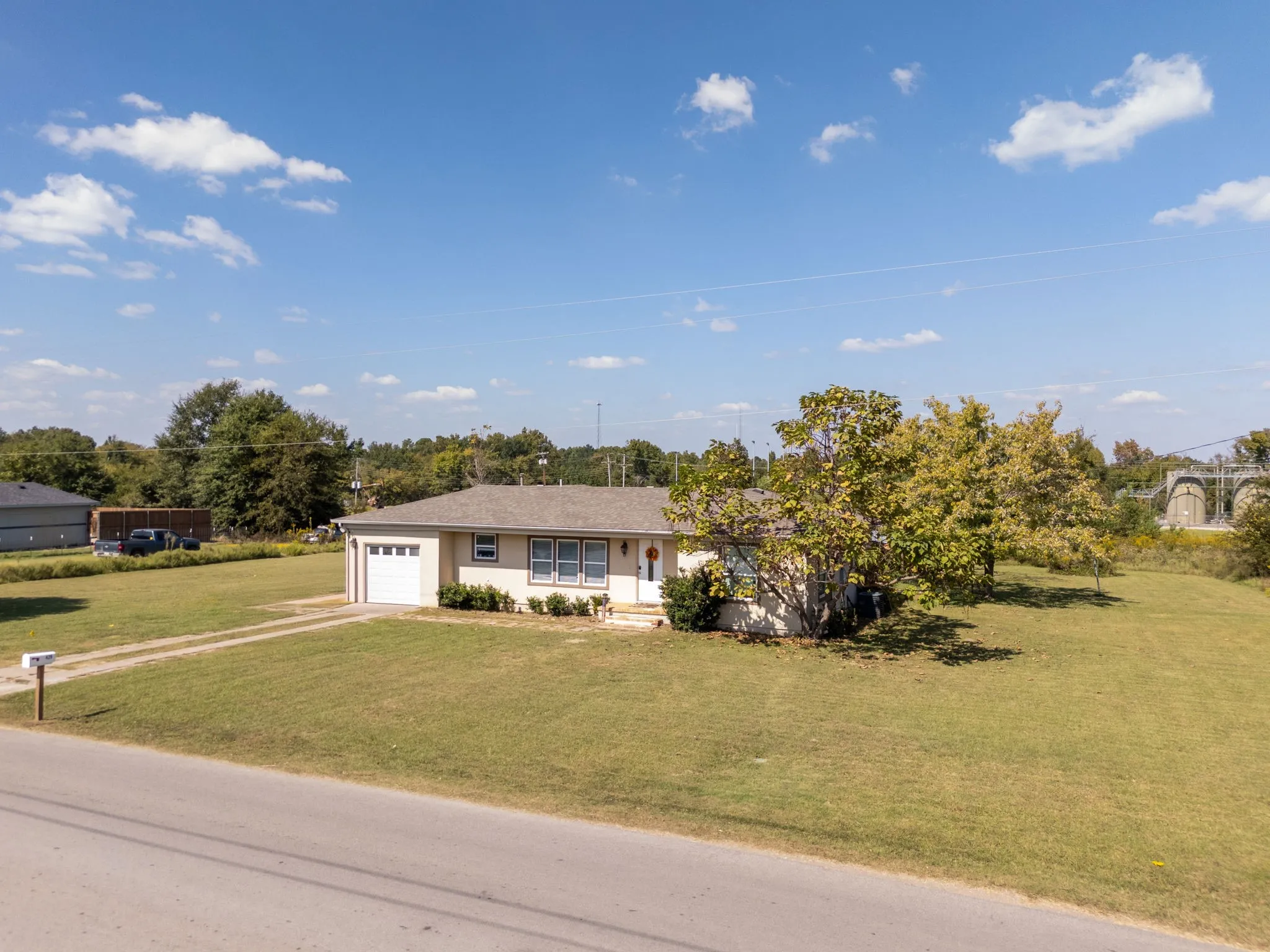 Single story home with a front yard, a porch, driveway, and a garage