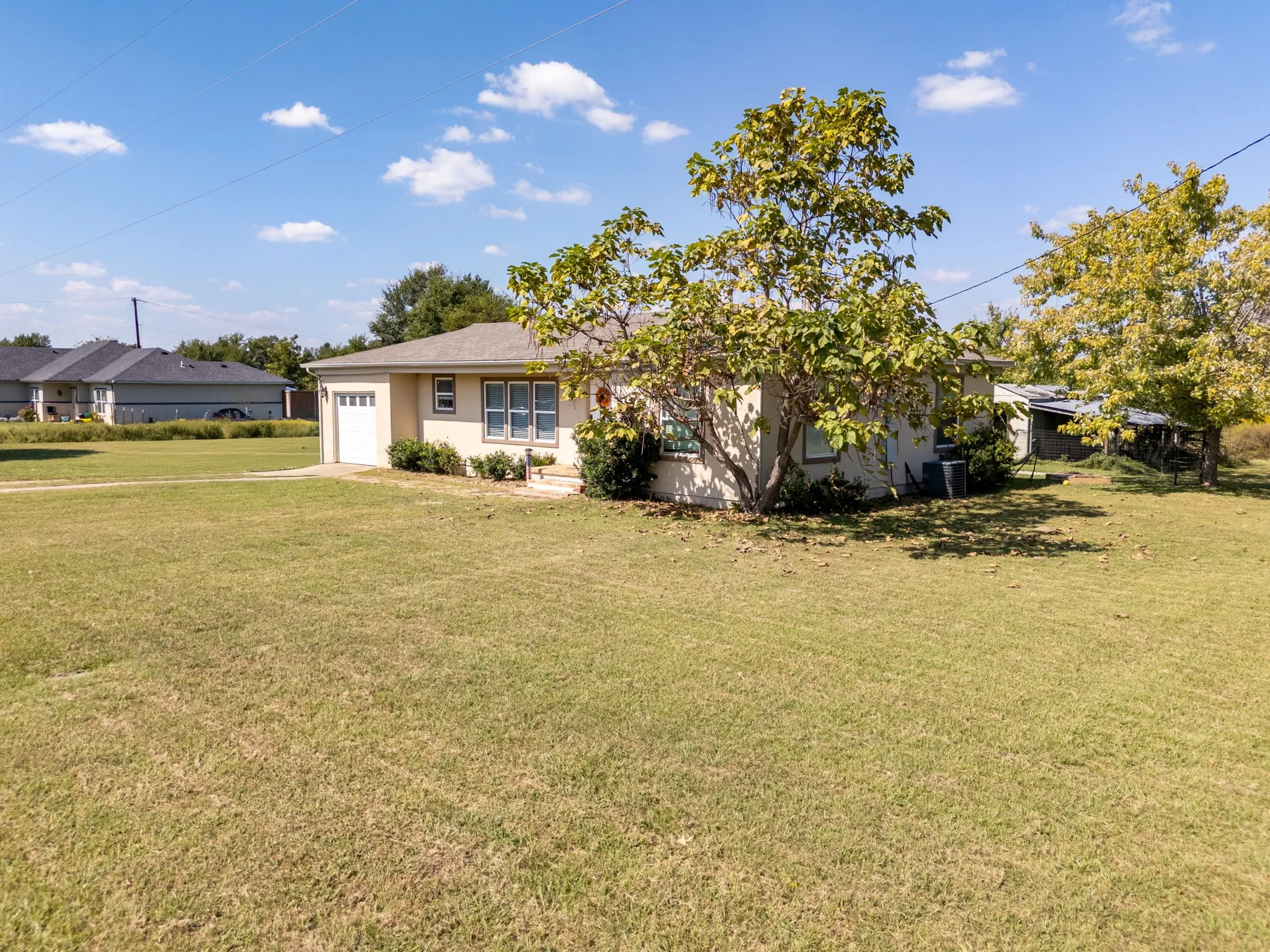 Ranch-style home with a front yard, an attached garage, and driveway