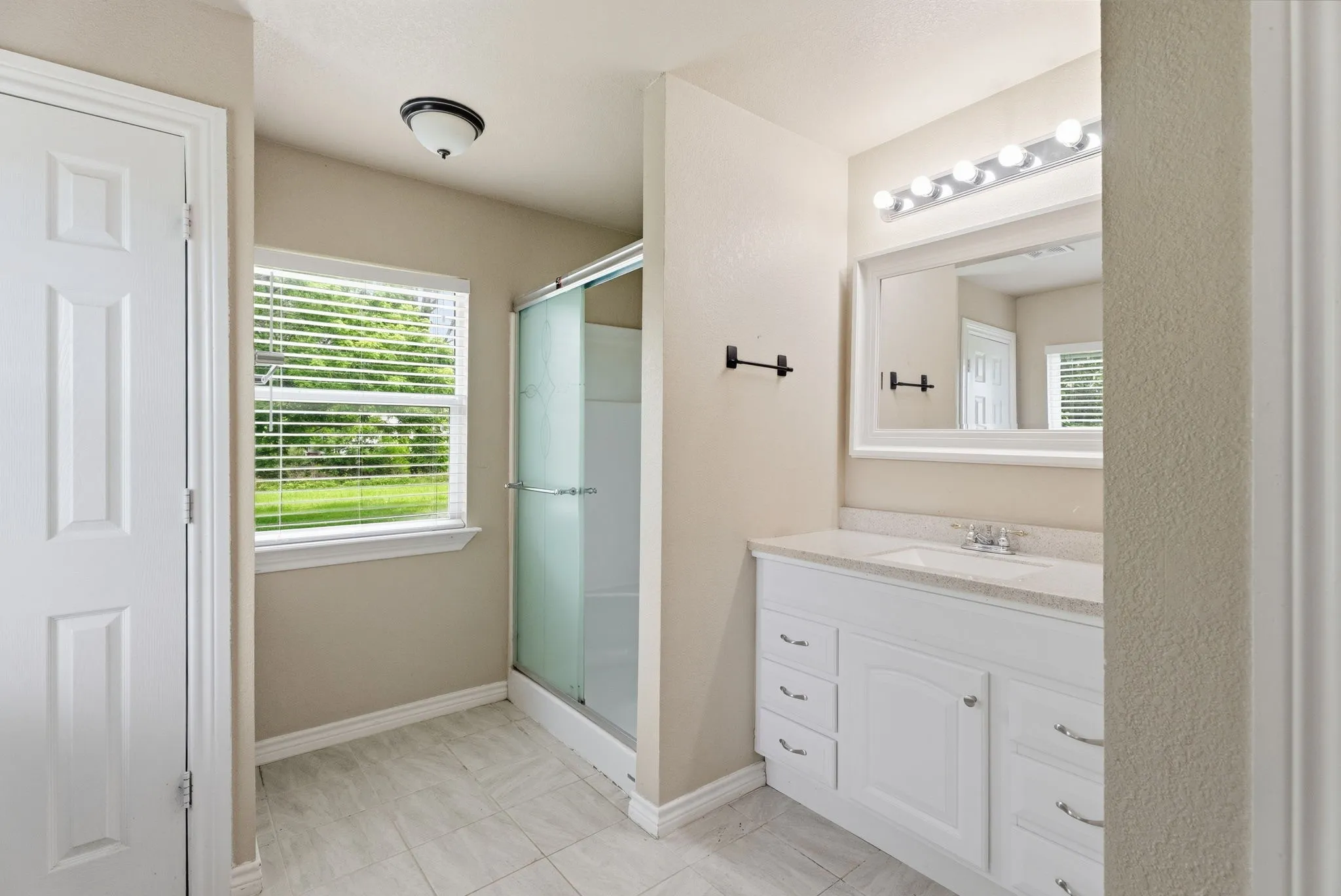 White vanity with integrated sink, framed mirror, and chrome lighting fixture