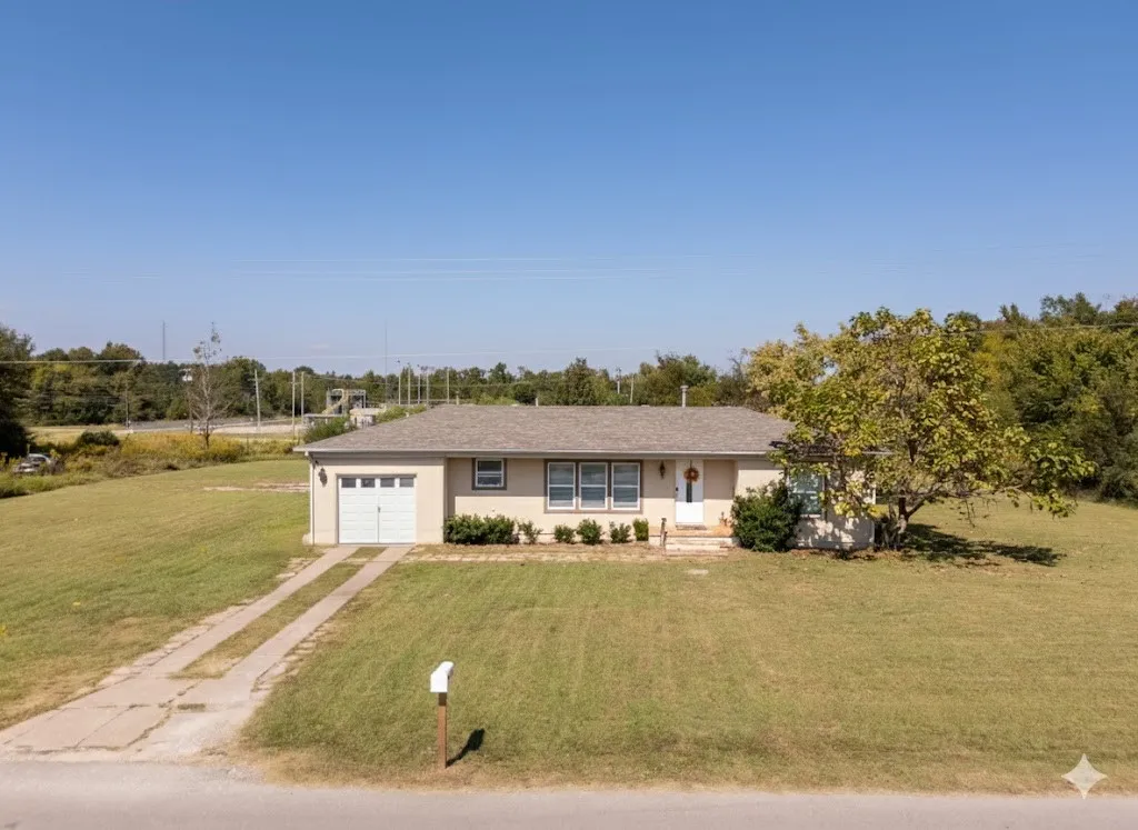 Single story home featuring a front lawn, driveway, an attached garage, and stucco siding