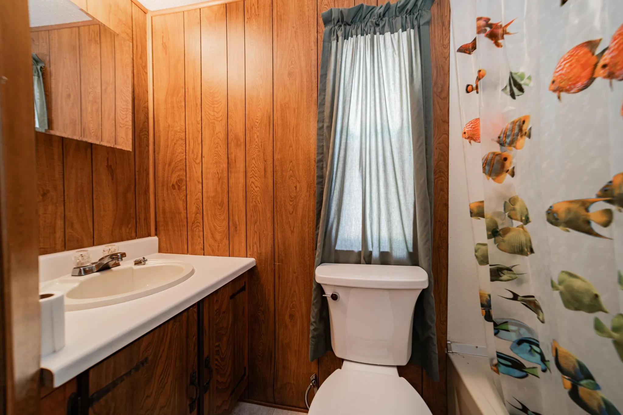 Bathroom with vanity, wooden walls, and shower / bath combination with curtain