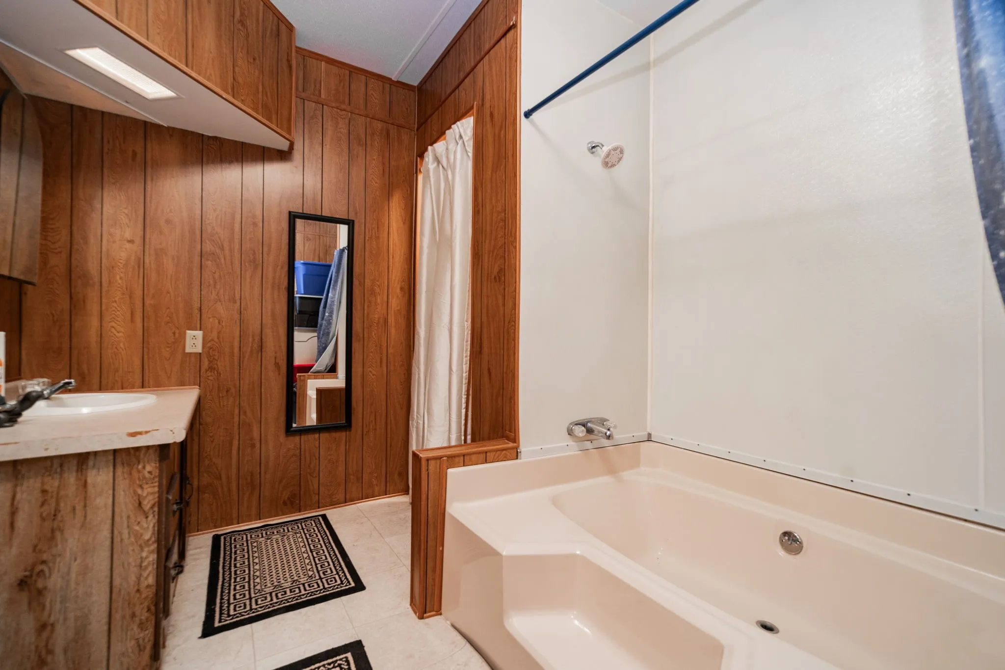 Bathroom featuring wood walls, vanity, and light tile patterned floors