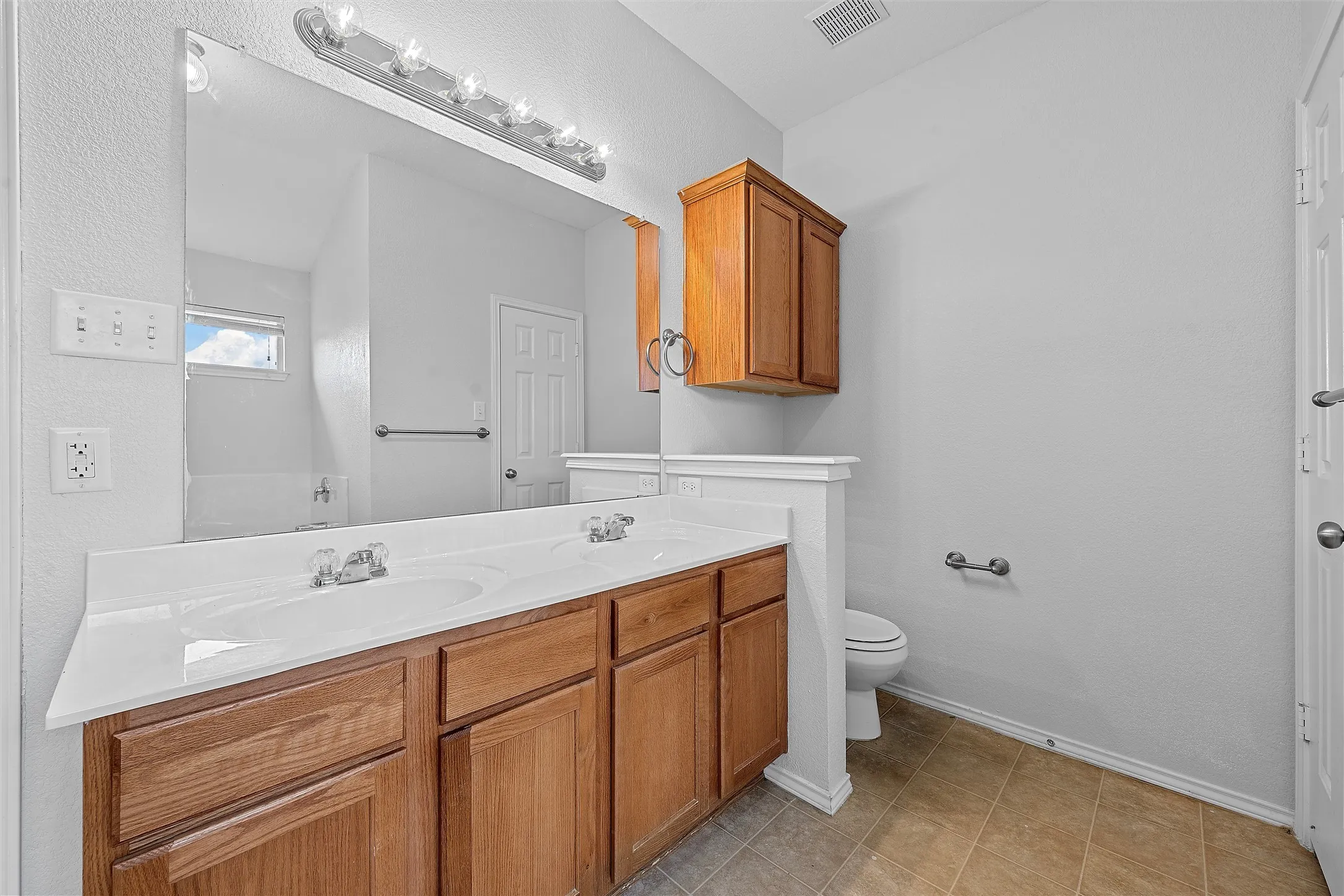 Full bathroom with double vanity and light tile patterned floors