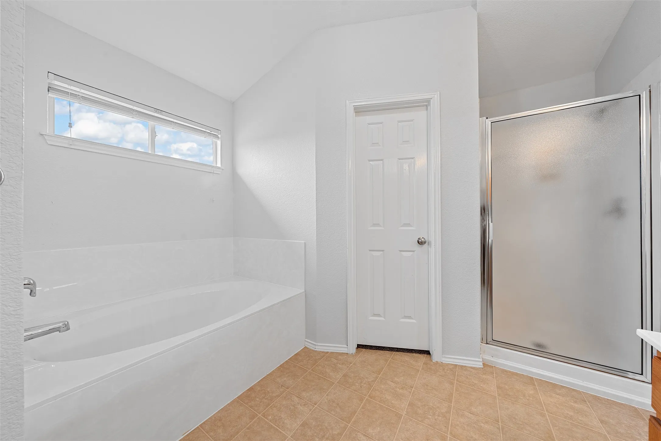 Full bathroom with a garden tub, a stall shower, light tile patterned flooring, and lofted ceiling