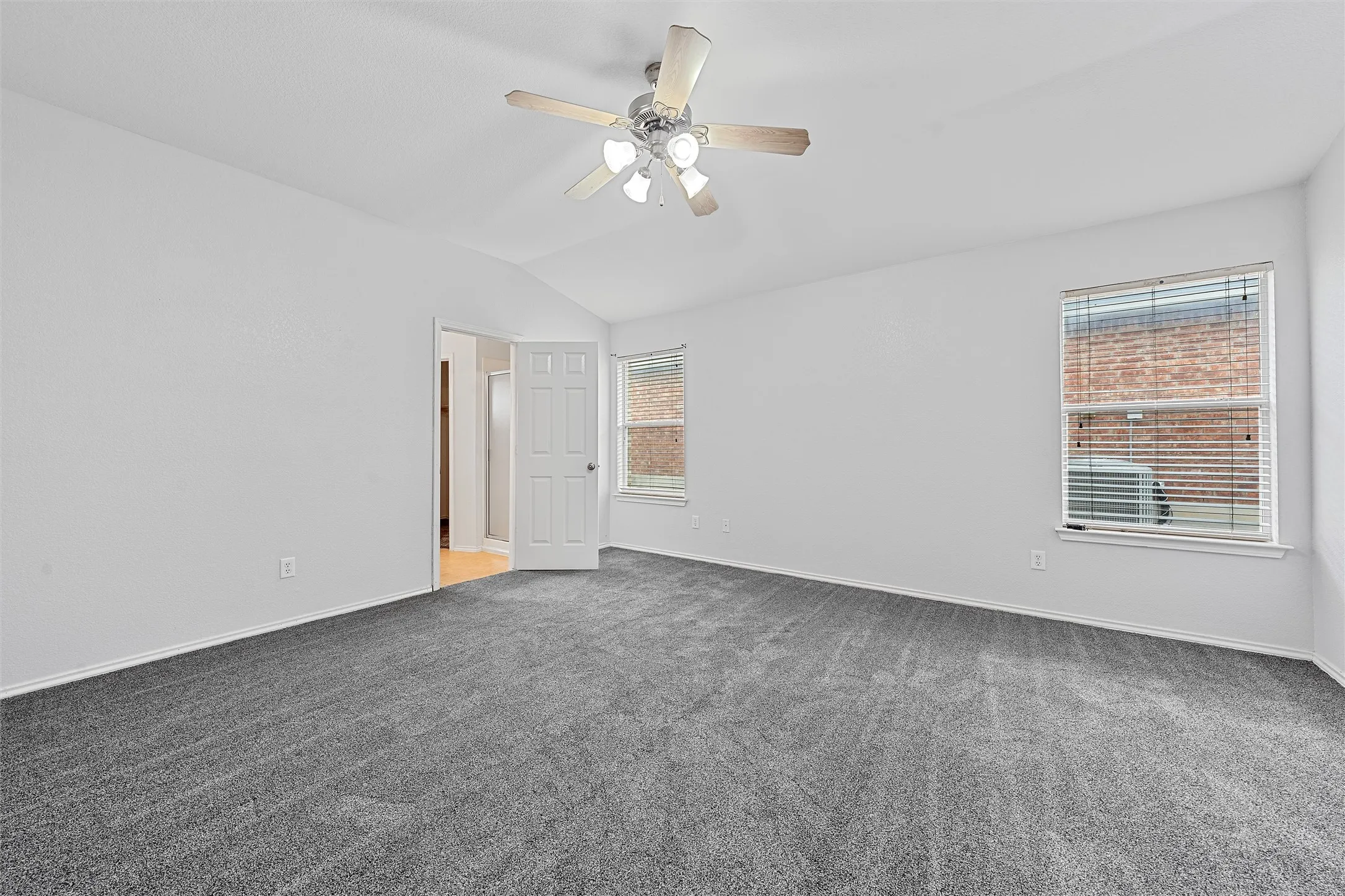 Unfurnished room with vaulted ceiling, light carpet, and a ceiling fan