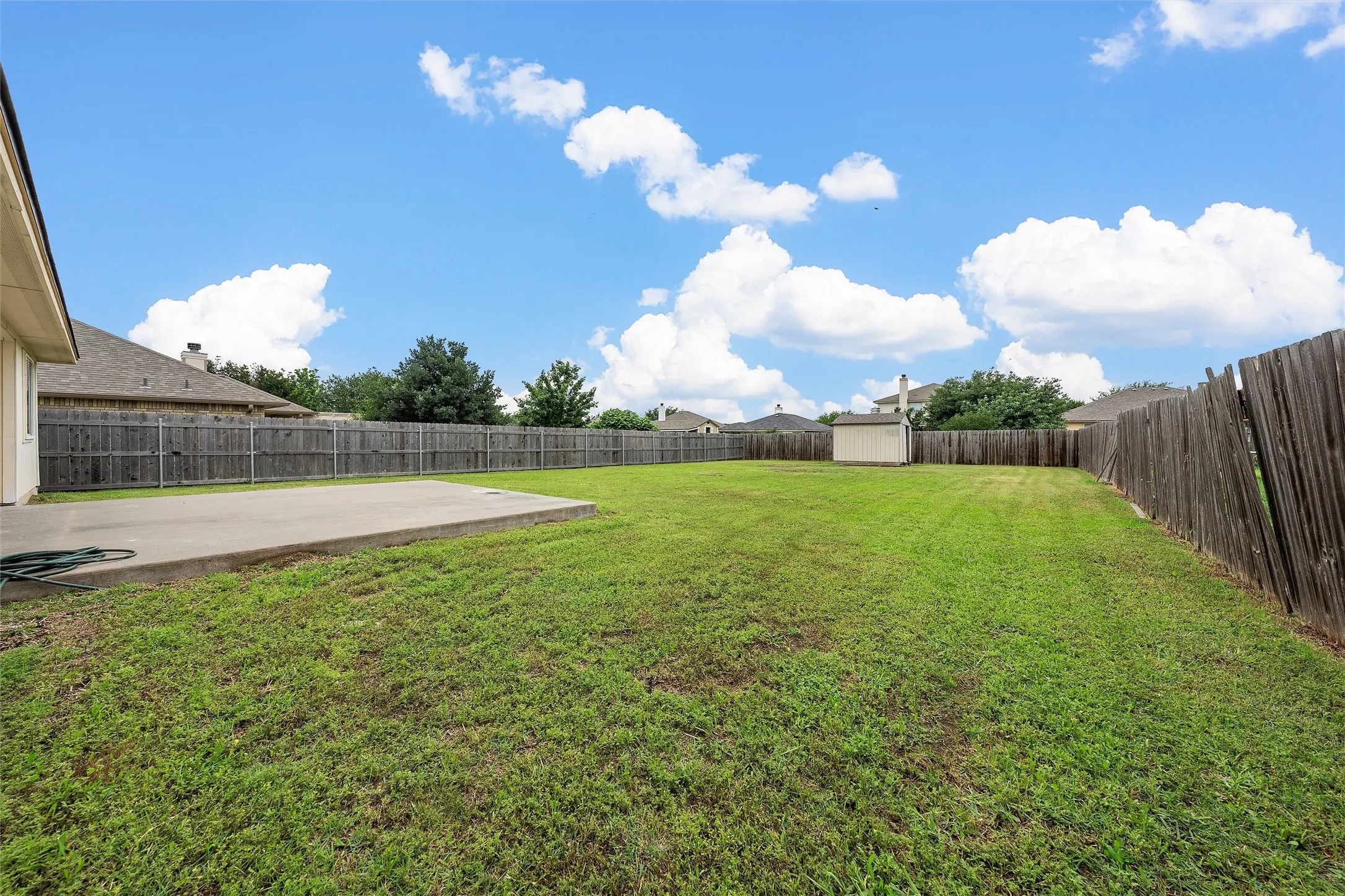Fenced backyard with a shed and a patio