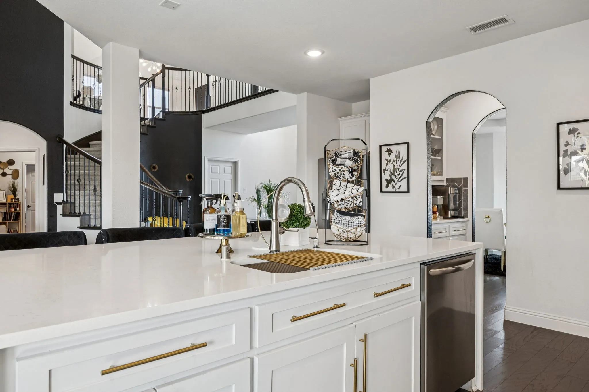 Kitchen with white cabinetry, arched walkways, light stone countertops, dark wood-style flooring, and open floor plan