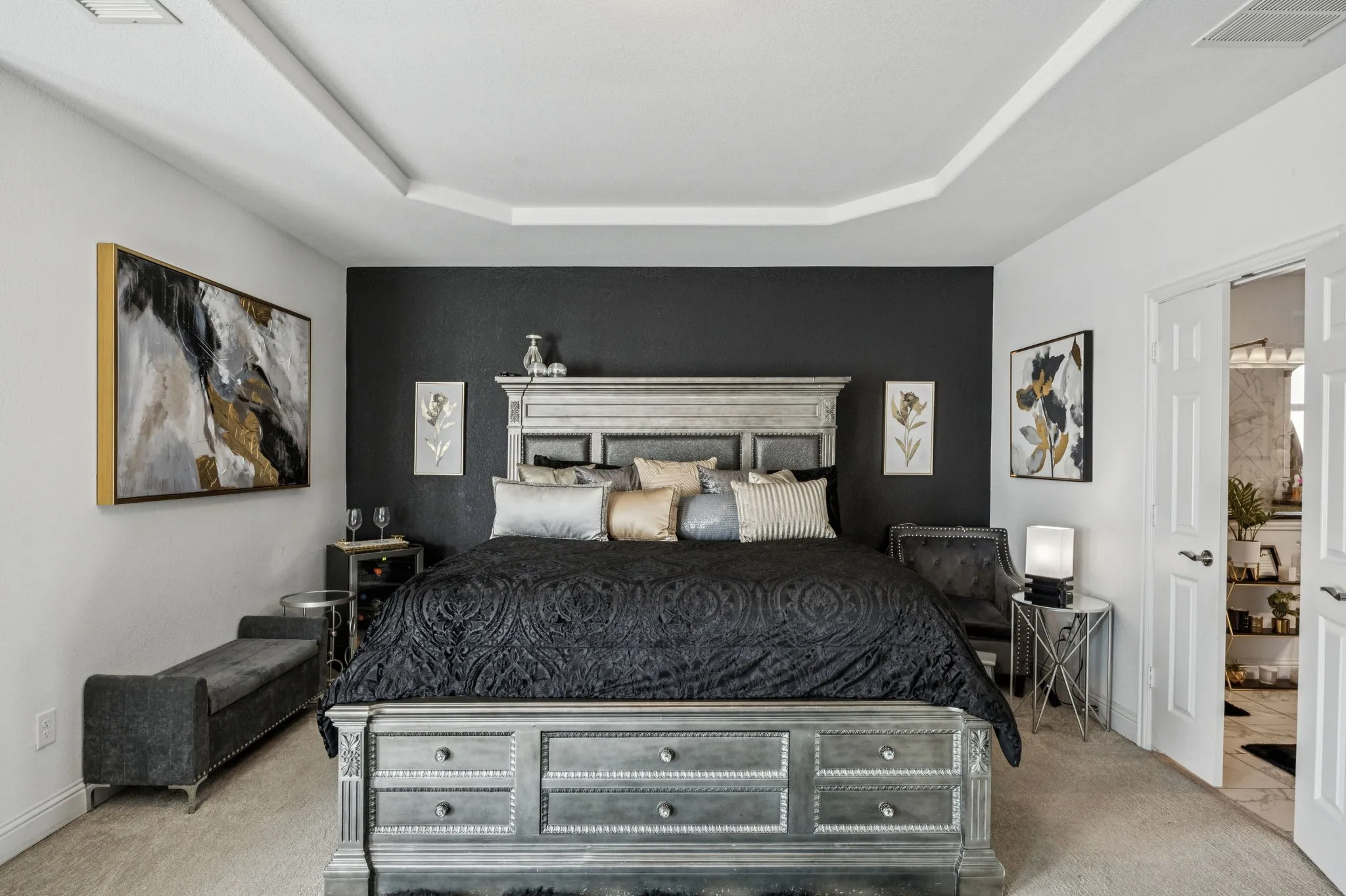 Bedroom with a raised ceiling, light carpet, and ensuite bathroom