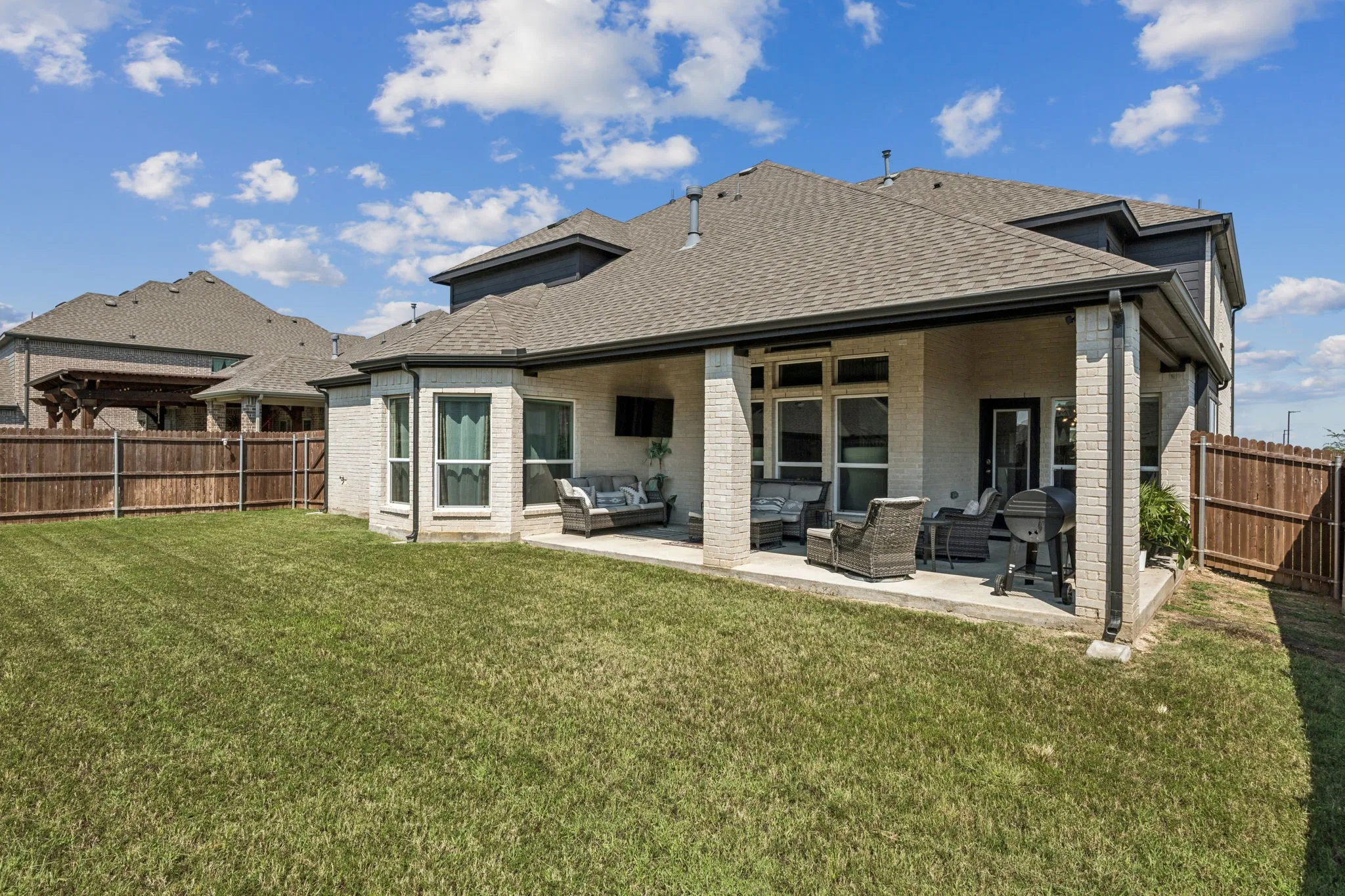 Rear view of property featuring an outdoor hangout area, a fenced backyard, roof with shingles, and a patio