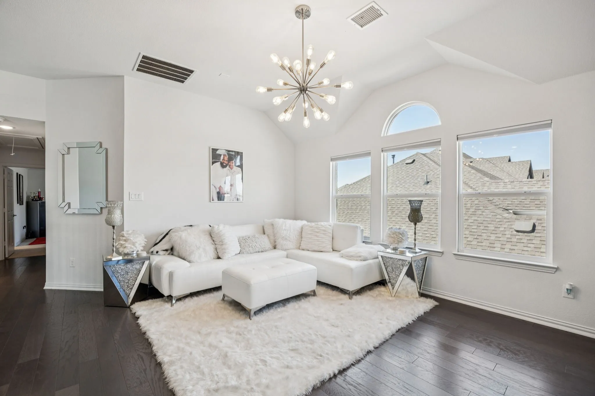 Living area featuring lofted ceiling, dark wood finished floors, attic access, and a chandelier
