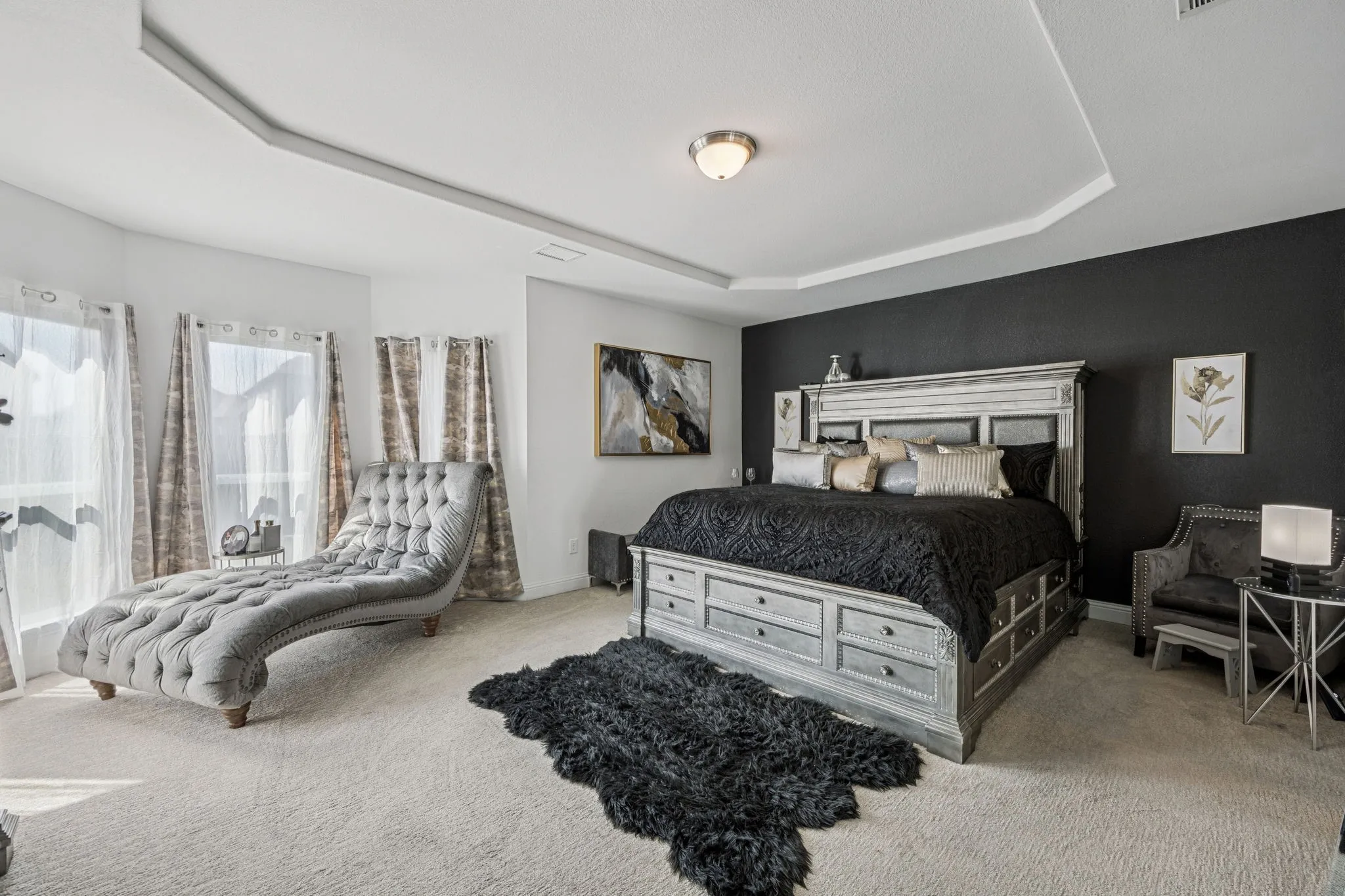 Carpeted bedroom with a tray ceiling and baseboards