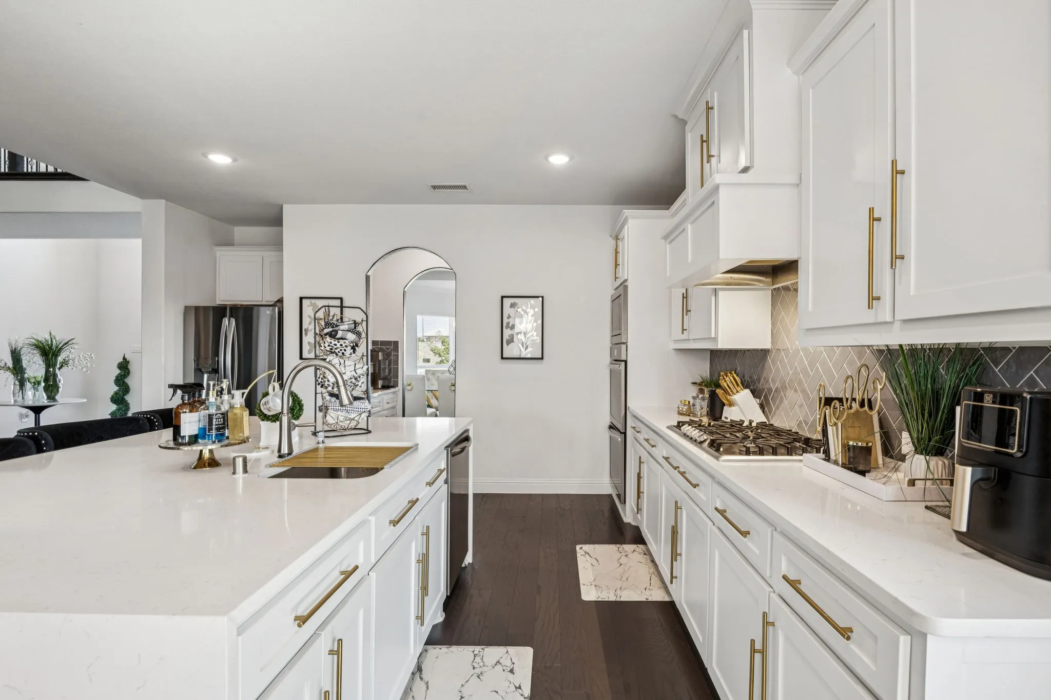 Kitchen featuring arched walkways, light stone counters, white cabinetry, dark wood-type flooring, and a large island