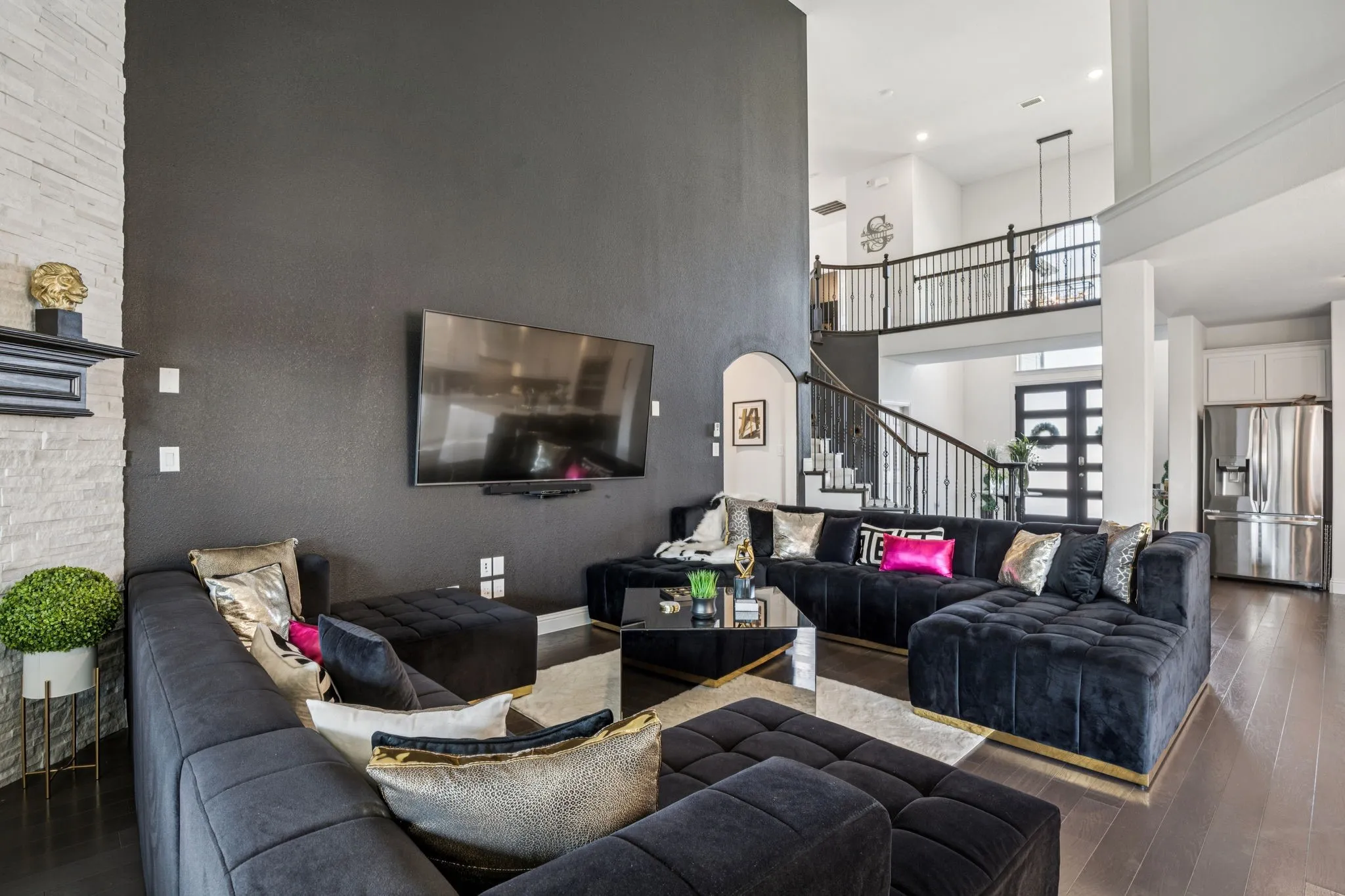 Living area with a towering ceiling, hardwood / wood-style flooring, stairs, arched walkways, and a fireplace