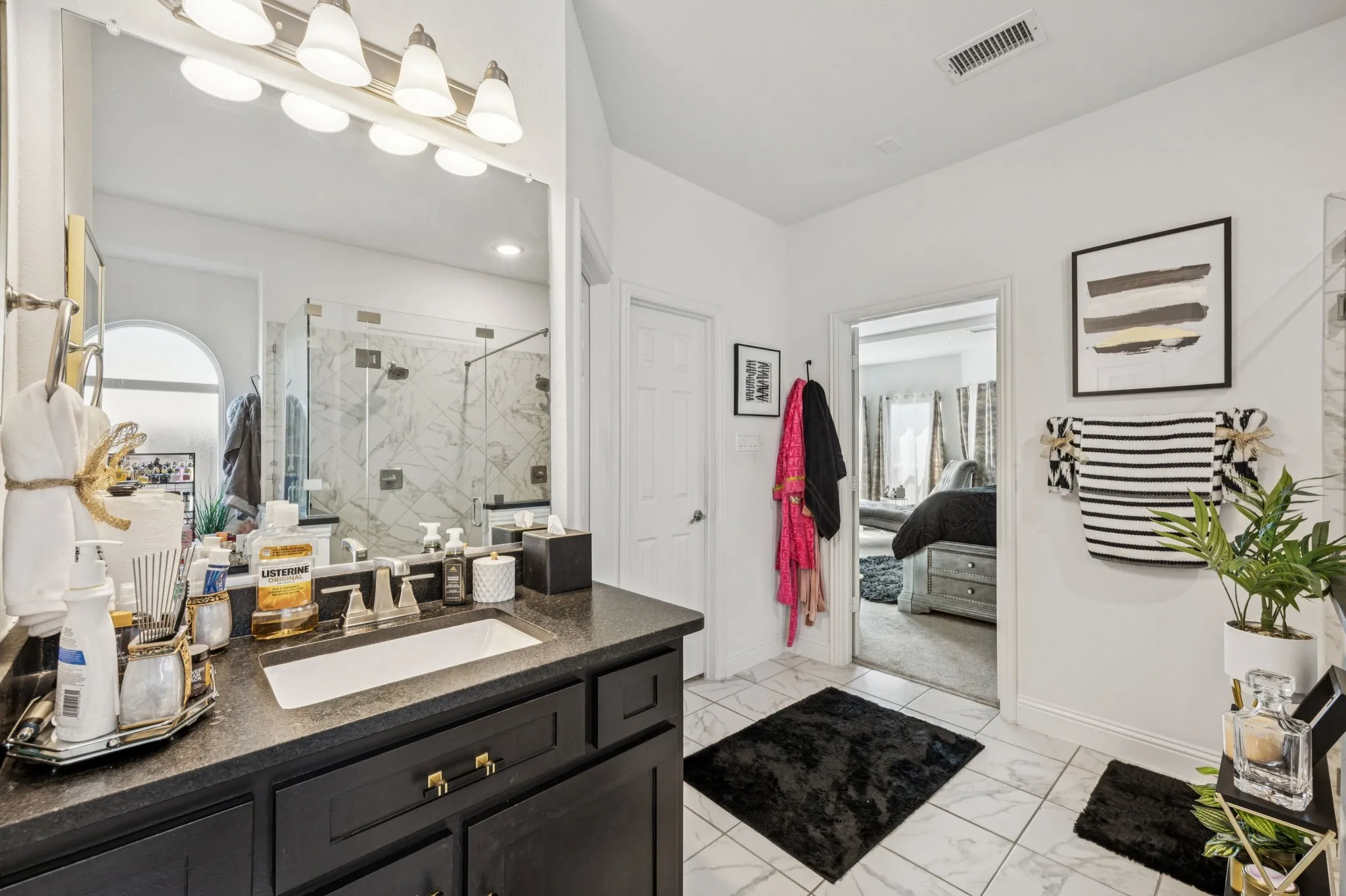 Ensuite bathroom with vanity, a marble finish shower, and light marble finish flooring