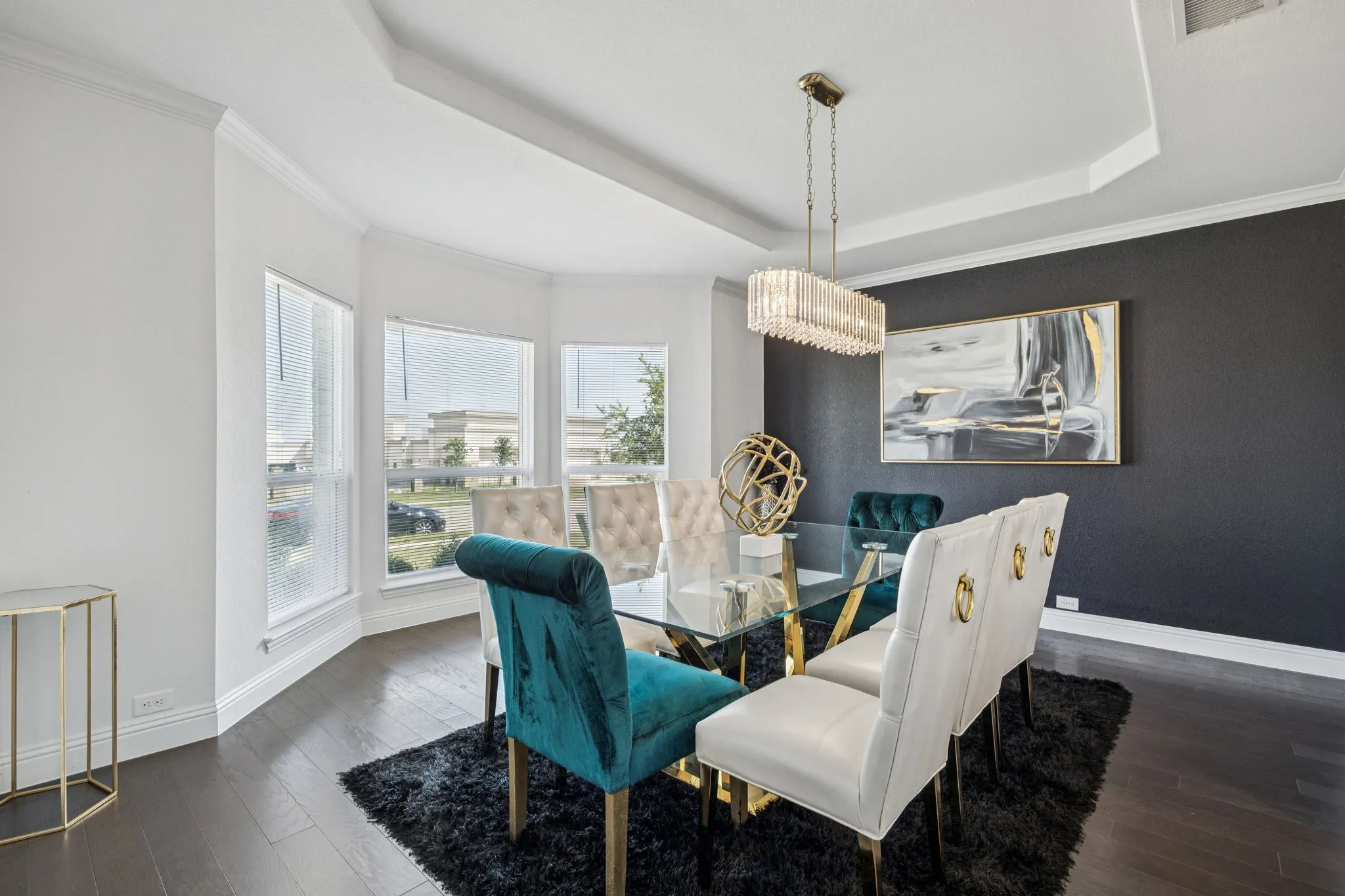 Dining area featuring a raised ceiling, dark wood finished floors, crown molding, and a chandelier