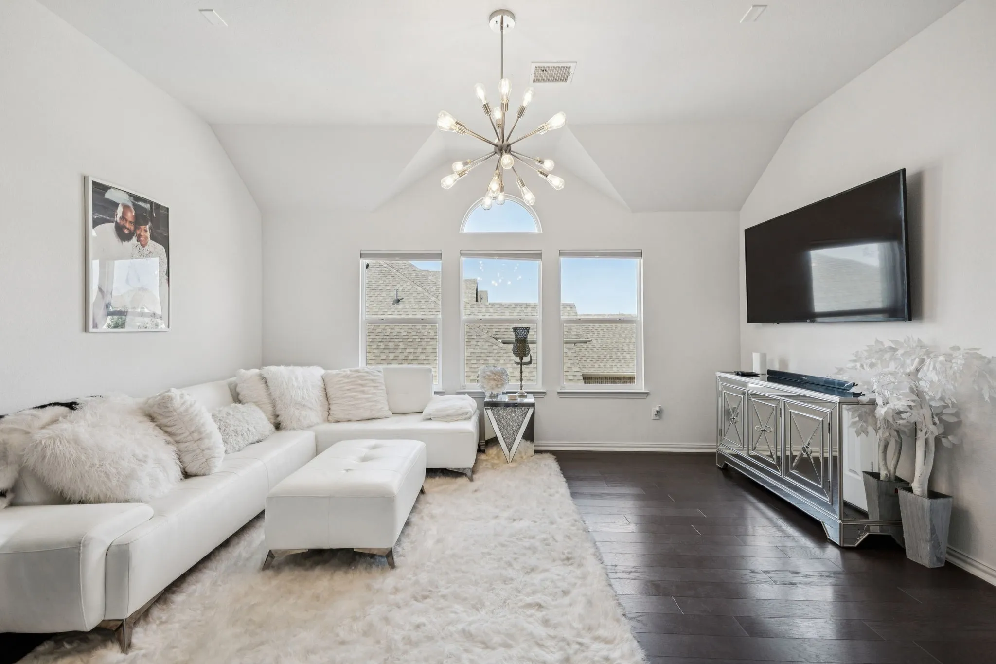 Living area featuring lofted ceiling, dark wood-style floors, and a chandelier