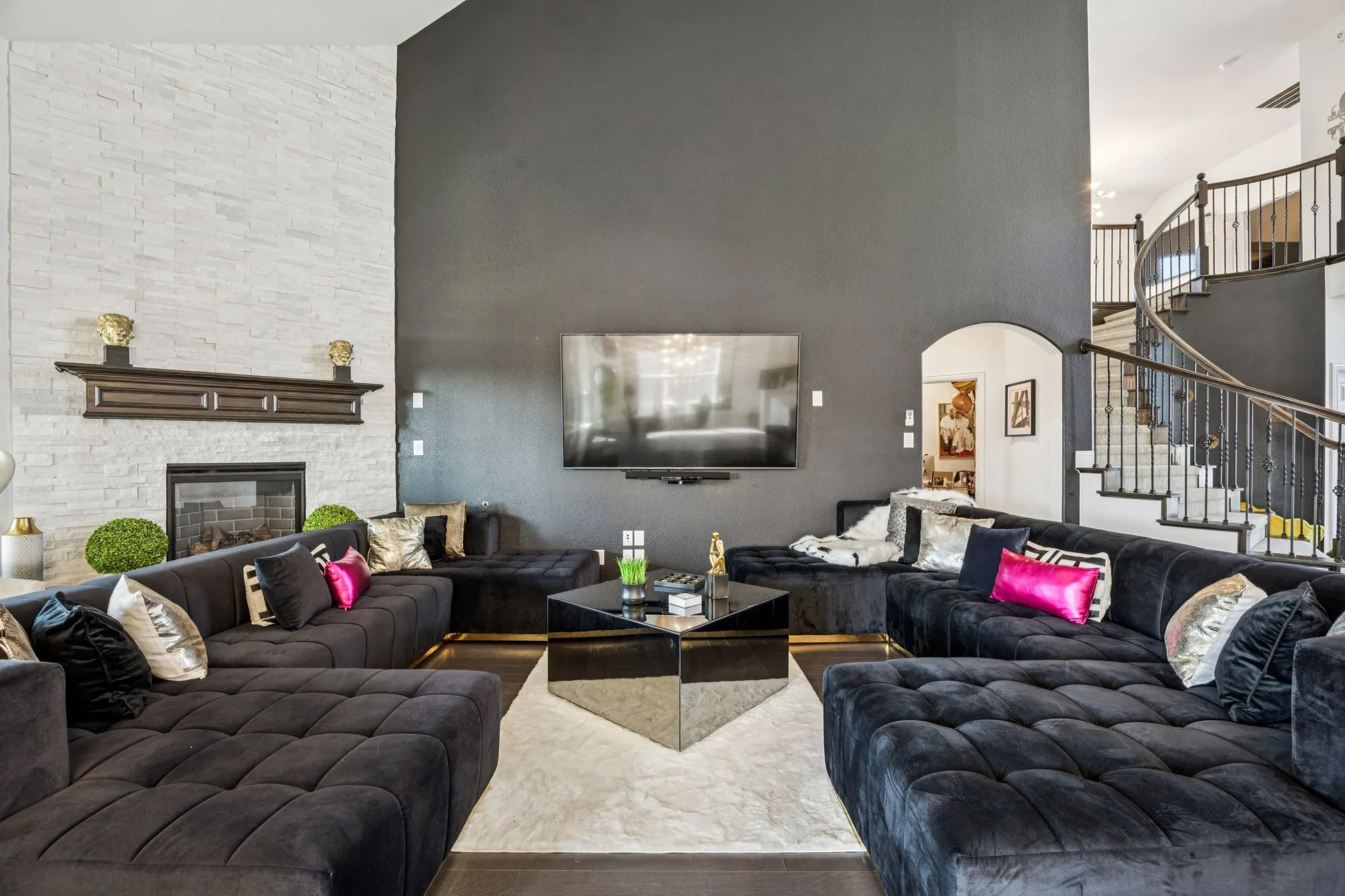Living area featuring high vaulted ceiling, stairs, a fireplace, arched walkways, and wood finished floors