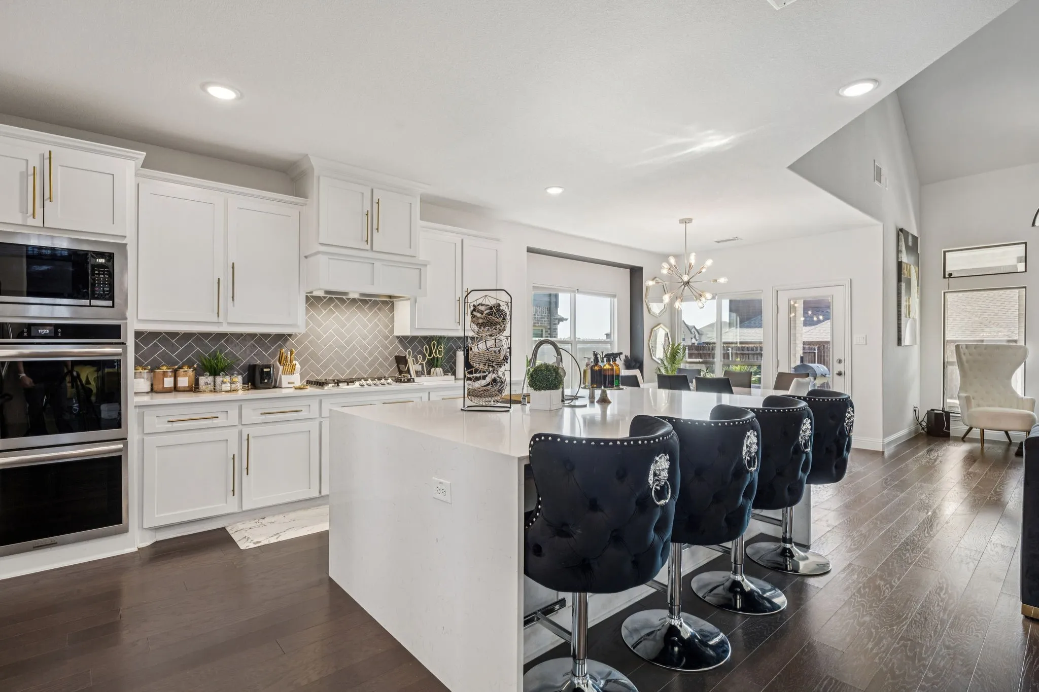 Kitchen featuring backsplash, white cabinetry, a breakfast bar area, stainless steel appliances, and dark wood finished floors