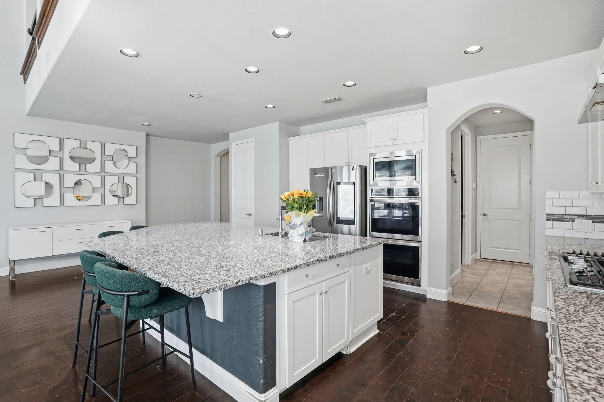 Kitchen with white cabinetry, arched walkways, recessed lighting, a breakfast bar, and a center island