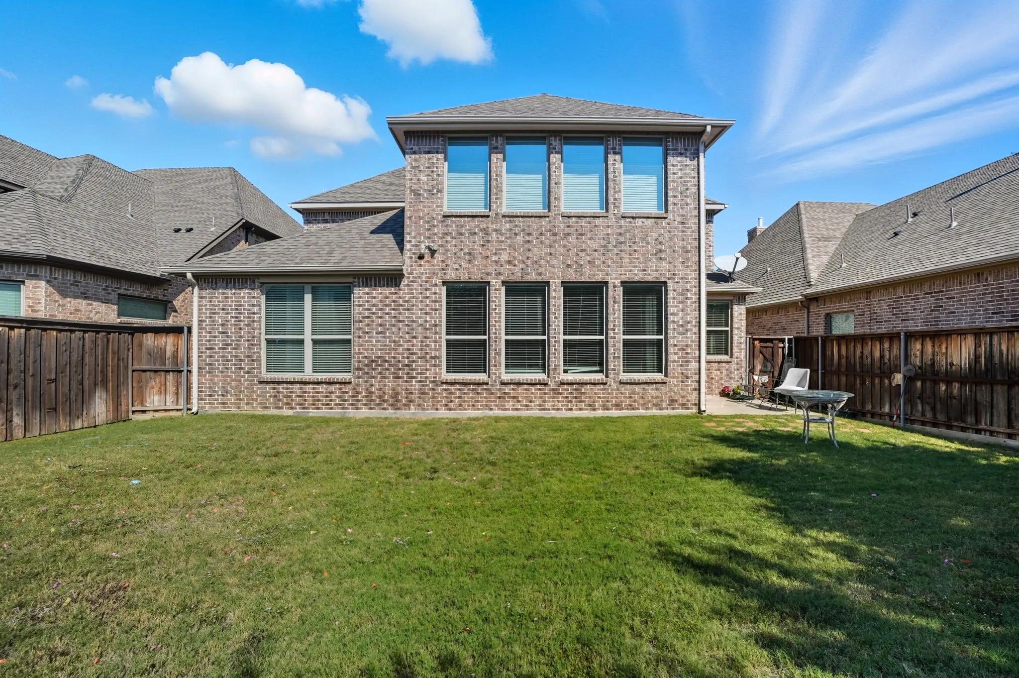 Rear view of property with brick siding, a fenced backyard, and a shingled roof