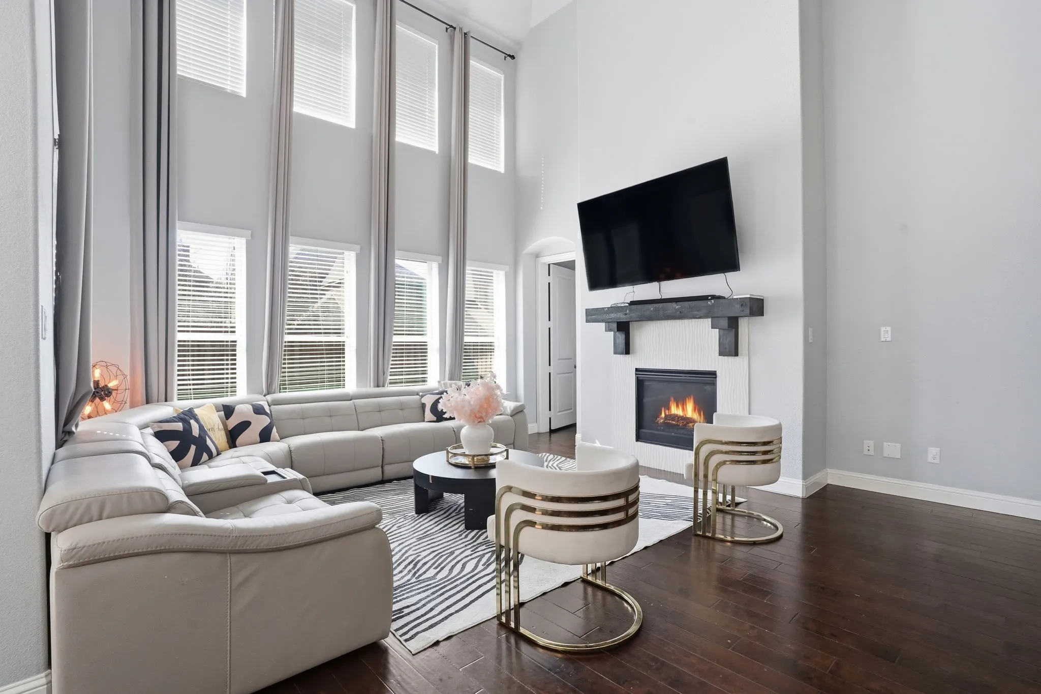Living area featuring a glass covered fireplace, a towering ceiling, and dark wood-style floors