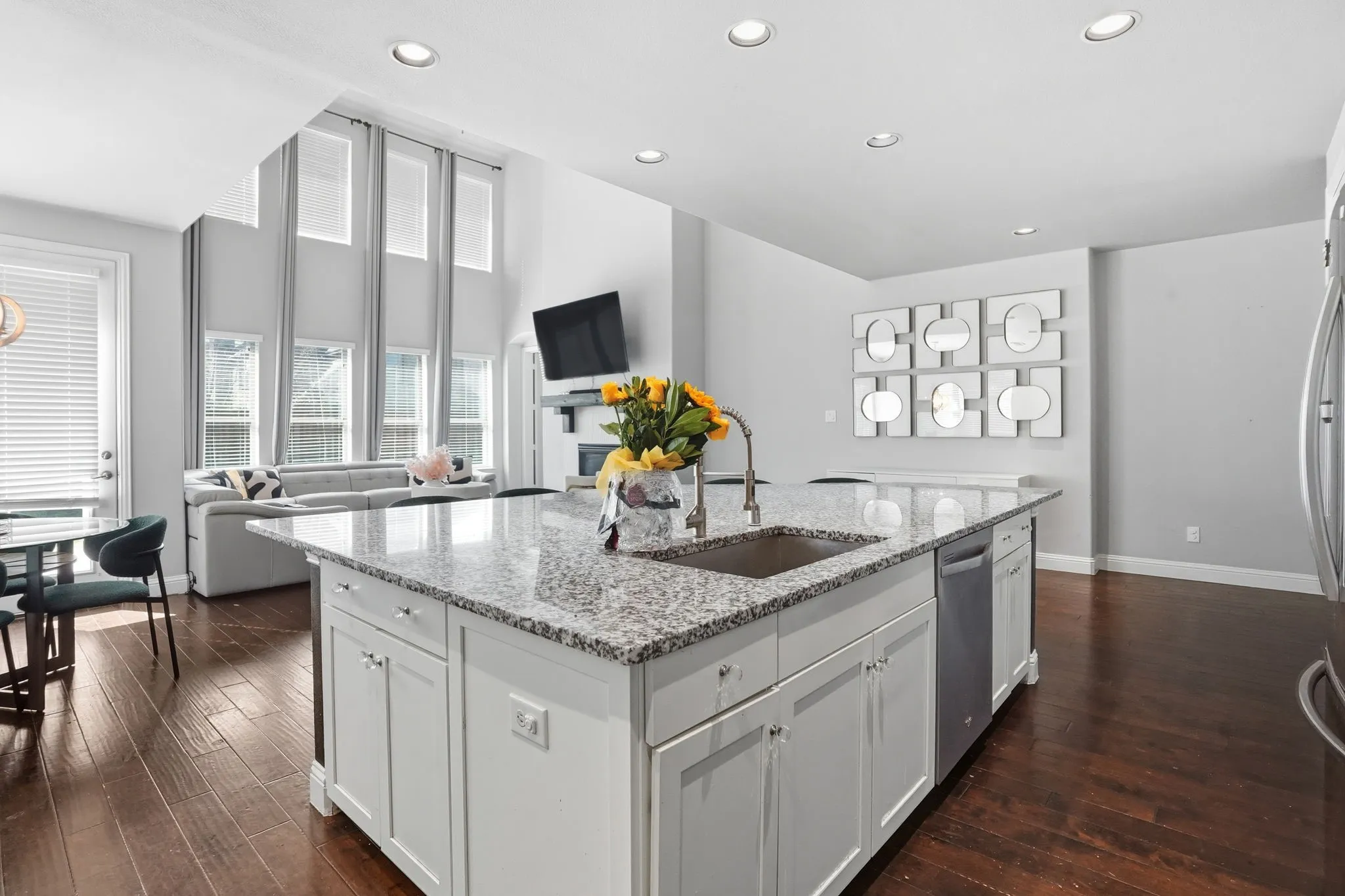 Kitchen featuring open floor plan, light stone countertops, white cabinets, and recessed lighting